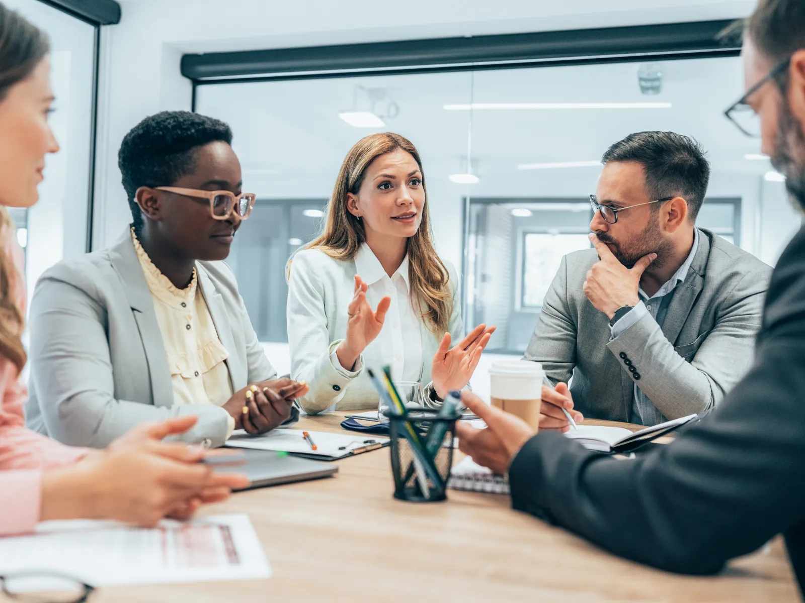 Diverse business team engaged in a collaborative meeting around a table in modern office environment.