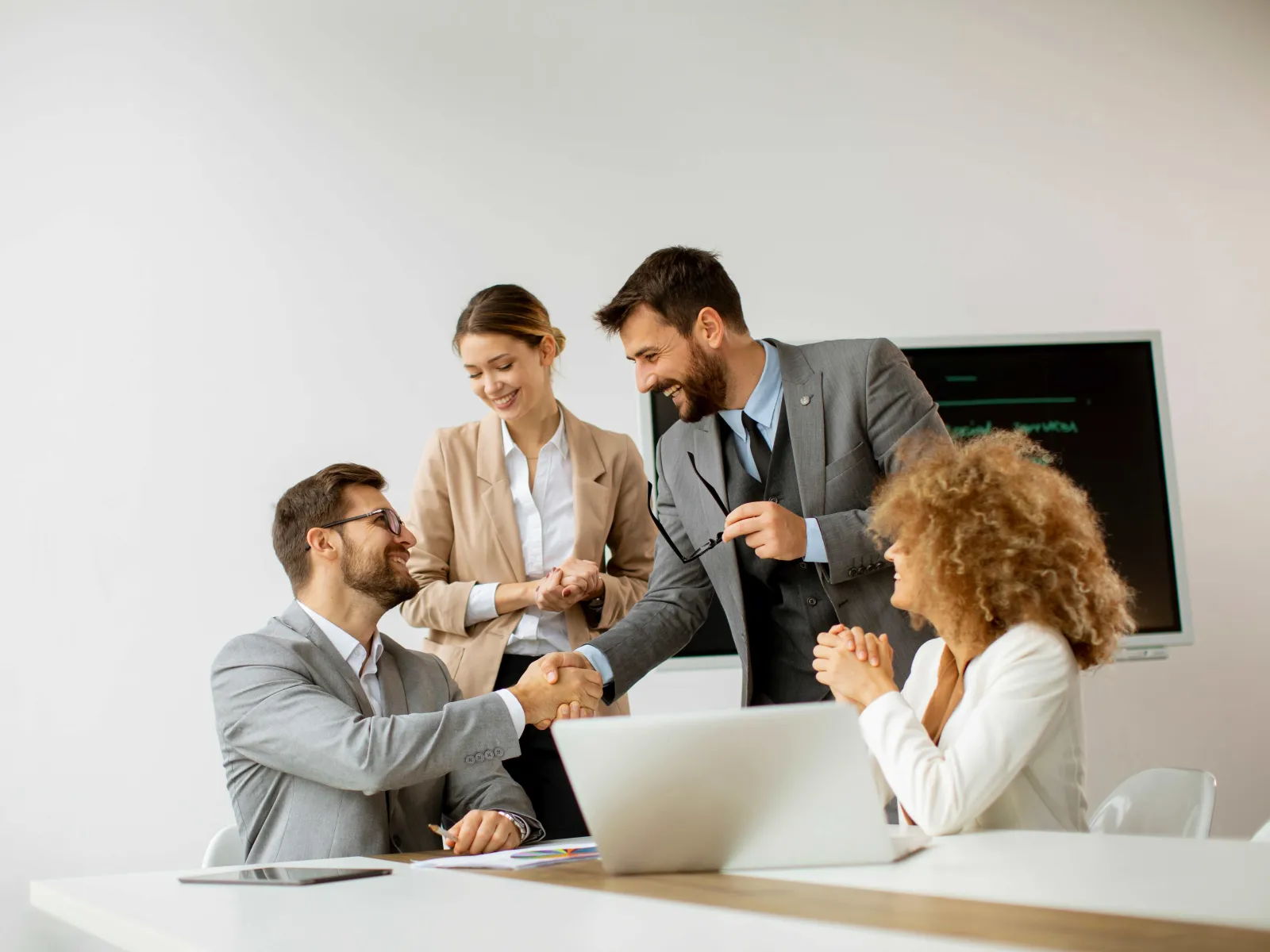 a group of people sitting at a table looking at a laptop