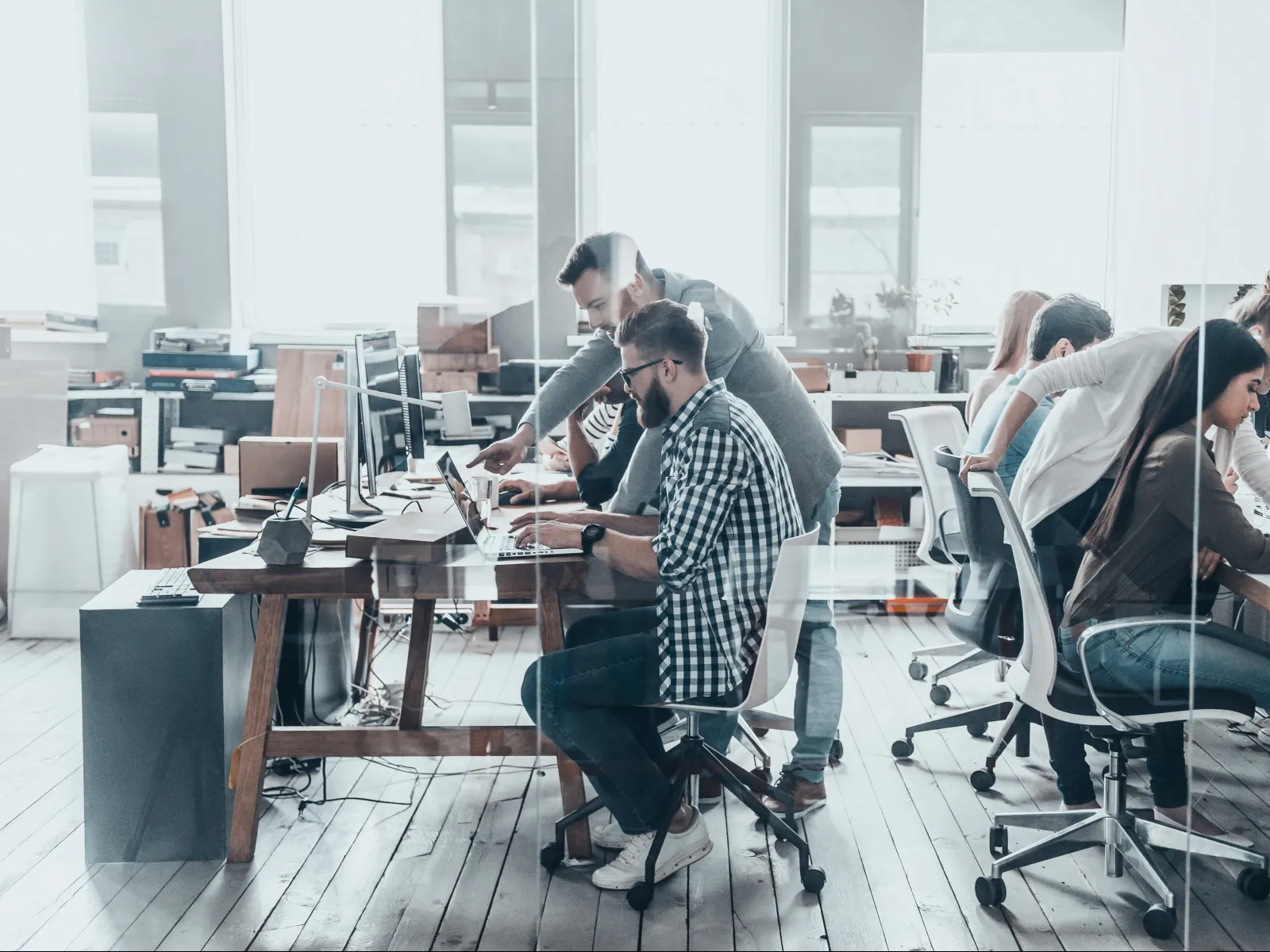 Team of young professionals collaborating and working on computers in a bright modern office space.