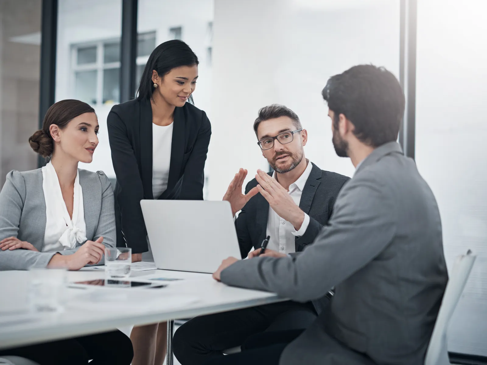 Business team collaborating during a meeting with laptop and documents in a modern office setting.