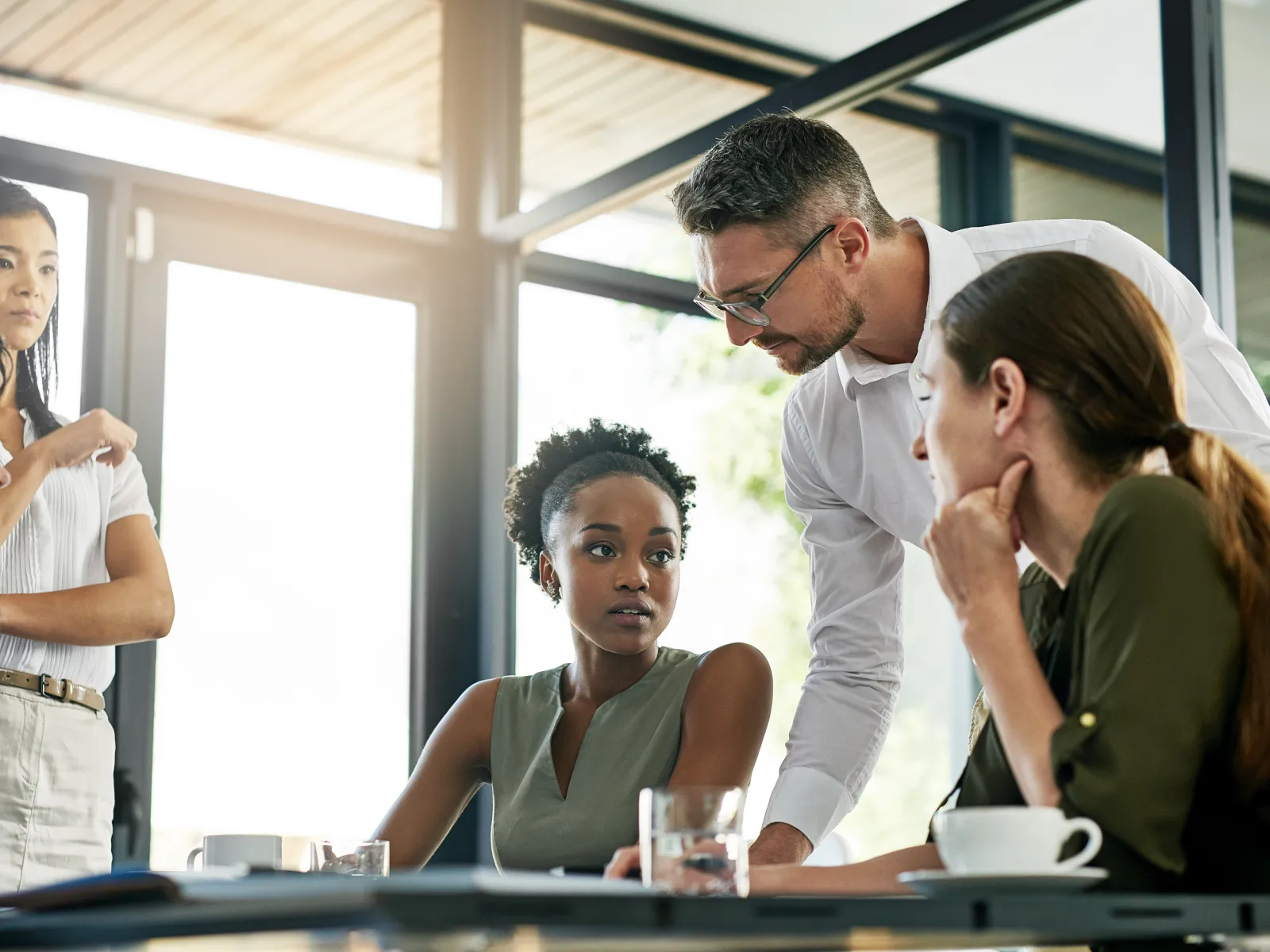Diverse business team engaged in a serious discussion around a table in a bright modern office.