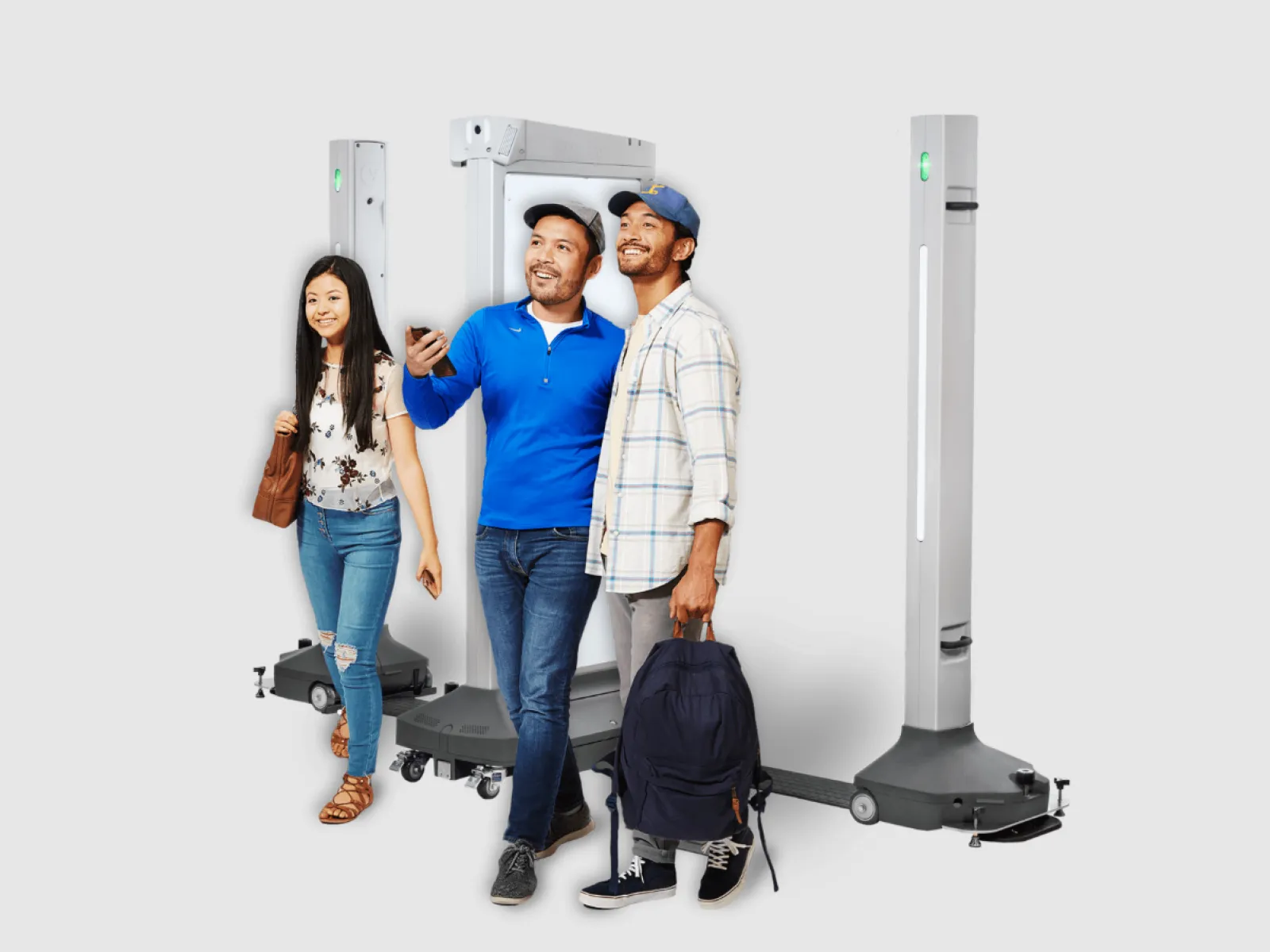Three diverse people walking through an evolv weapons detection portal in a bright setting.