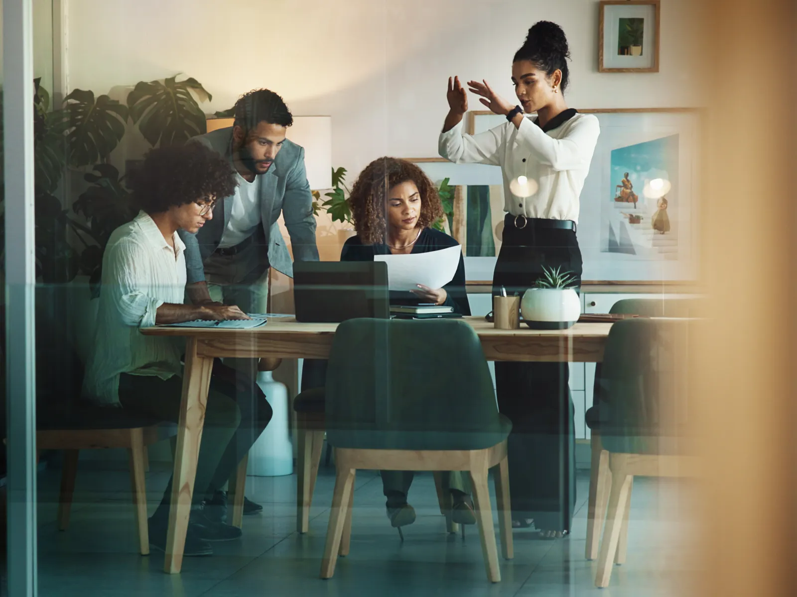 Diverse group of professionals collaborating around a table in a modern office with laptops and documents