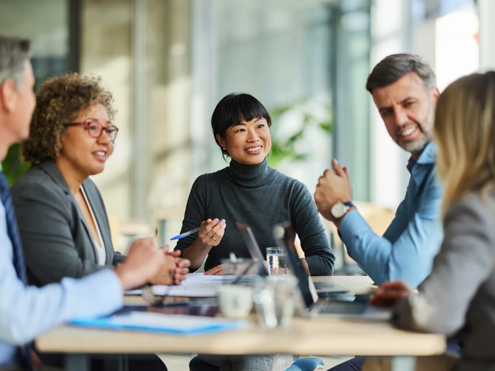 Diverse business team engaged in a lively discussion during a meeting in a bright office setting.