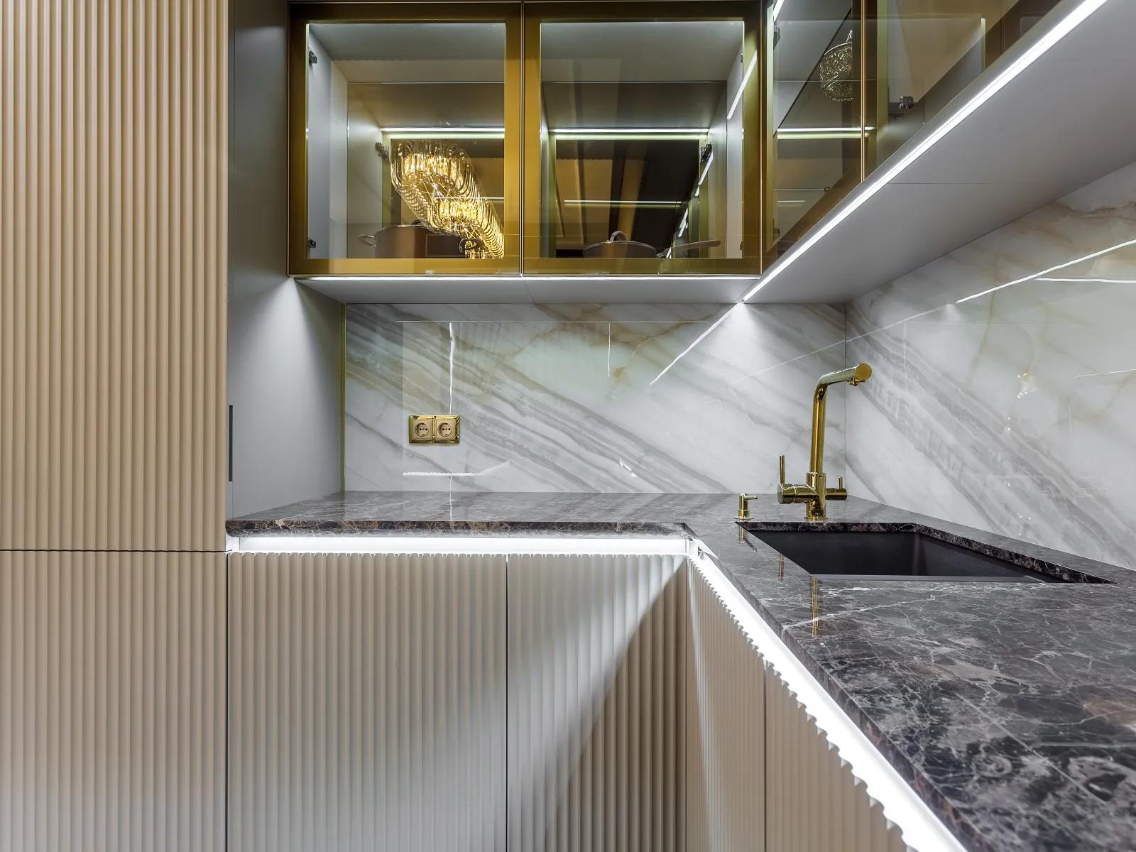 Modern kitchen corner with marble countertops, gold faucet, glass cabinets, and ambient LED lighting.