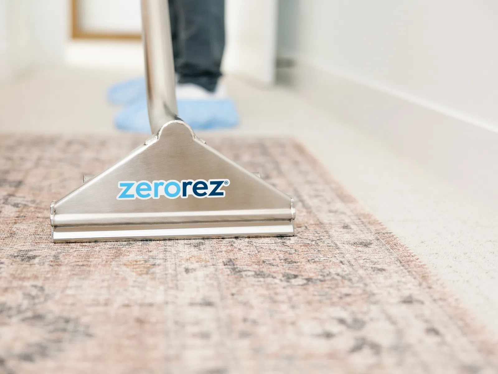 Professional carpet cleaning machine with Zerorez logo cleans a patterned rug on a light floor indoors.