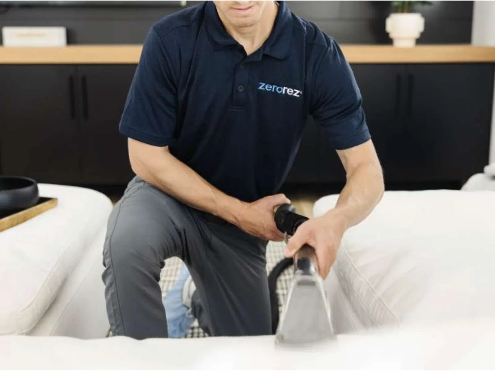 Professional cleaner using specialized equipment to clean a white sofa in a modern living room.