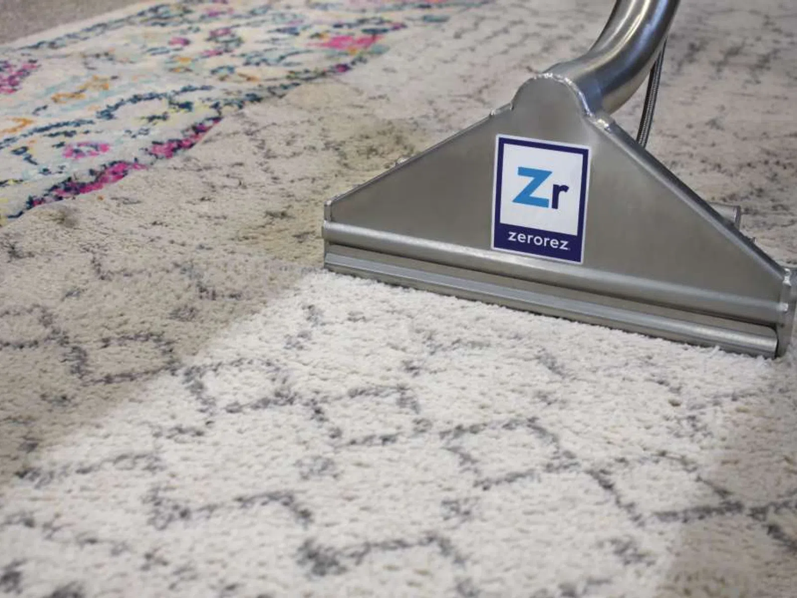 Carpet cleaning machine cleaning a patterned rug, showing a clear clean strip on the carpet.