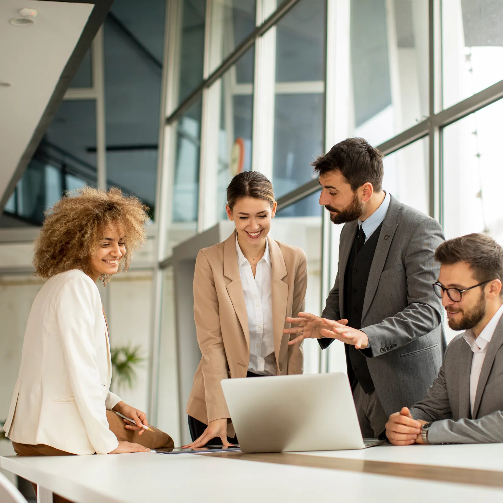 Professional team collaborating at a modern office with a laptop and natural lighting.