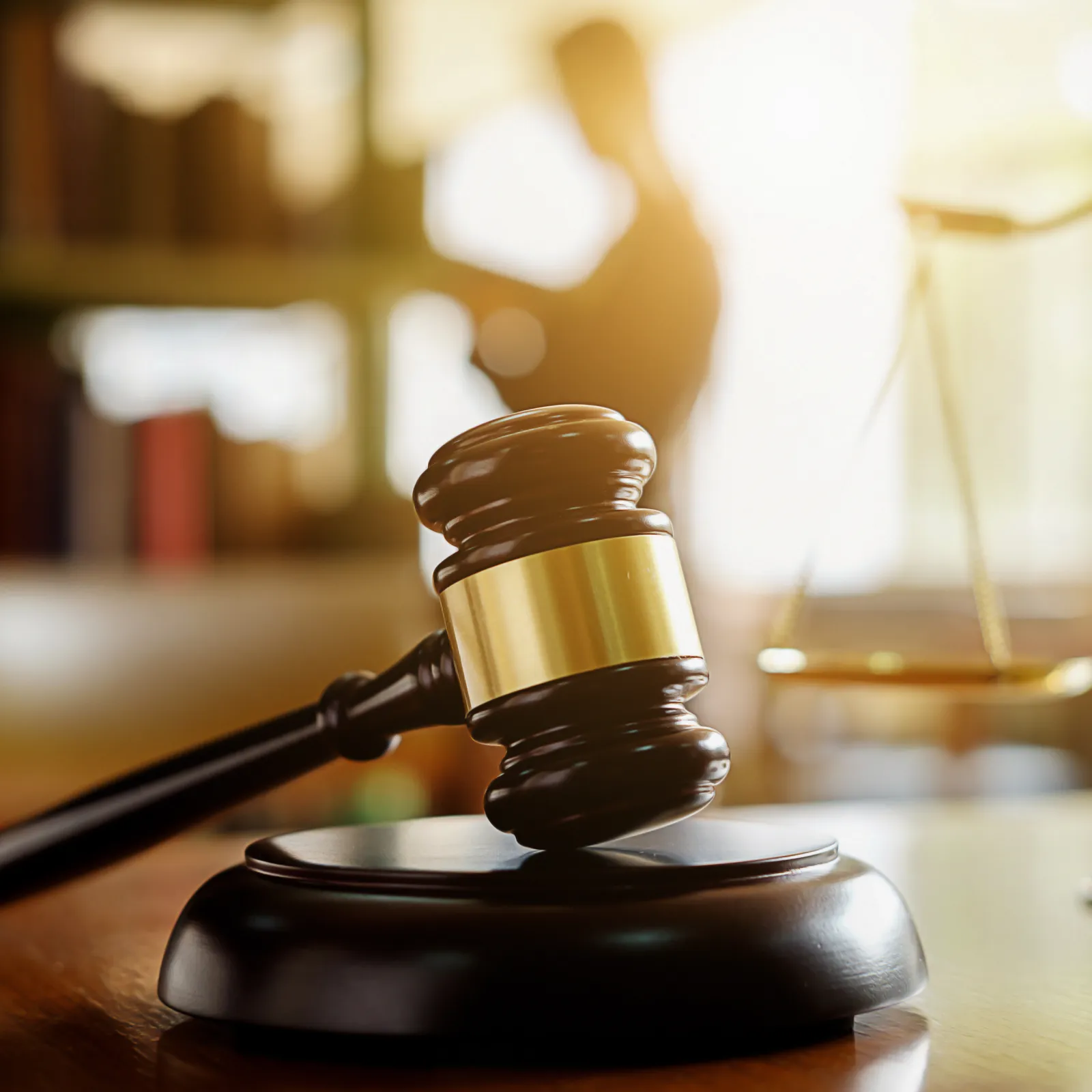 A close-up of a gavel and scales of justice, symbolizing law and legal proceedings in a courtroom setting.