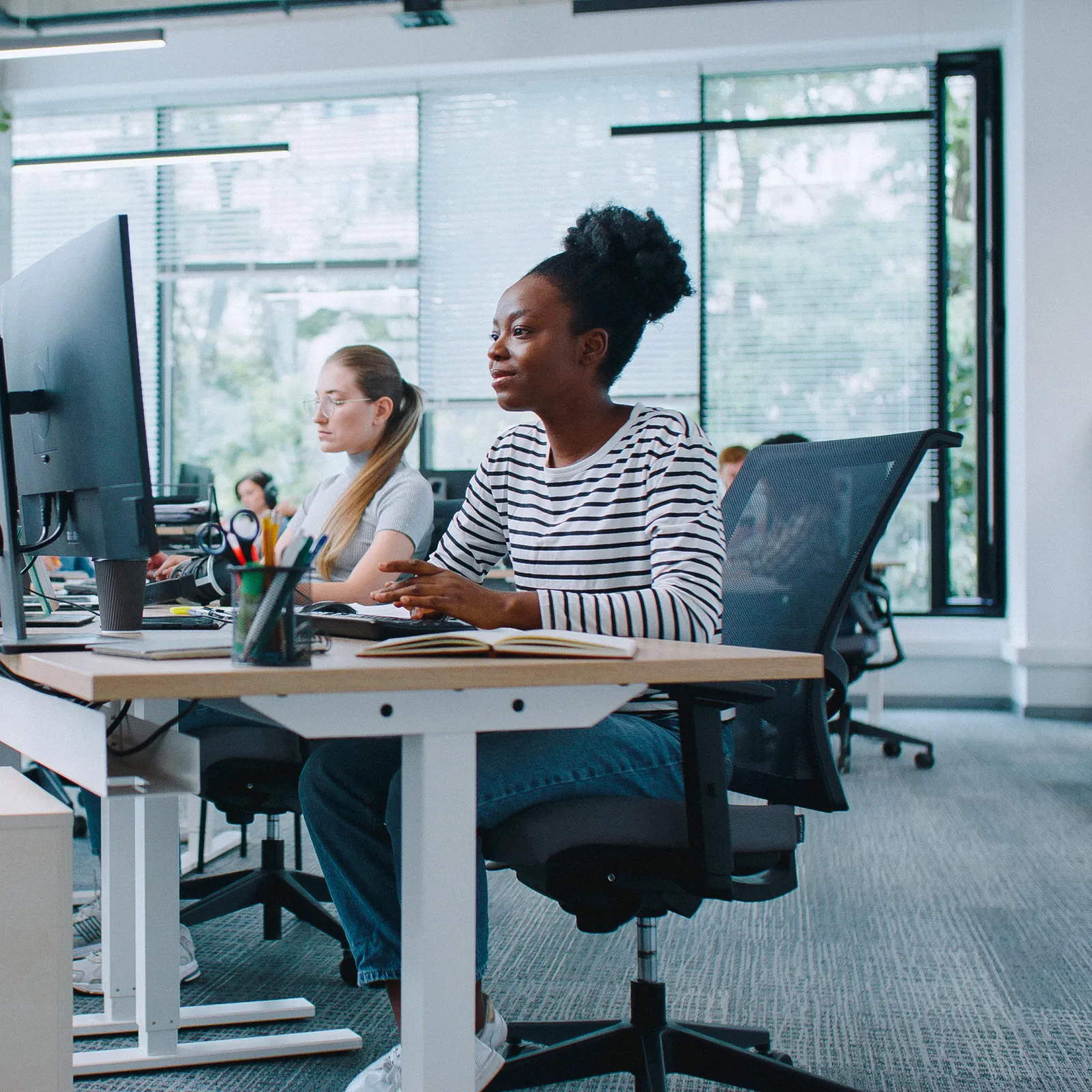A modern office environment with diverse employees working at desks with computers.