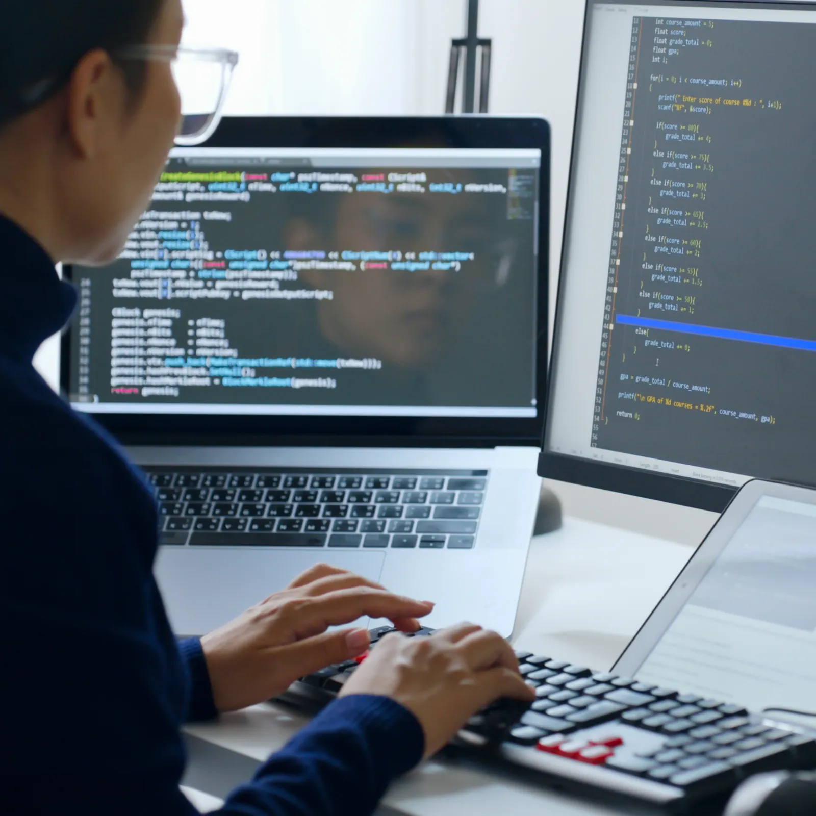 A woman coding on multiple screens, focusing on software development and programming.