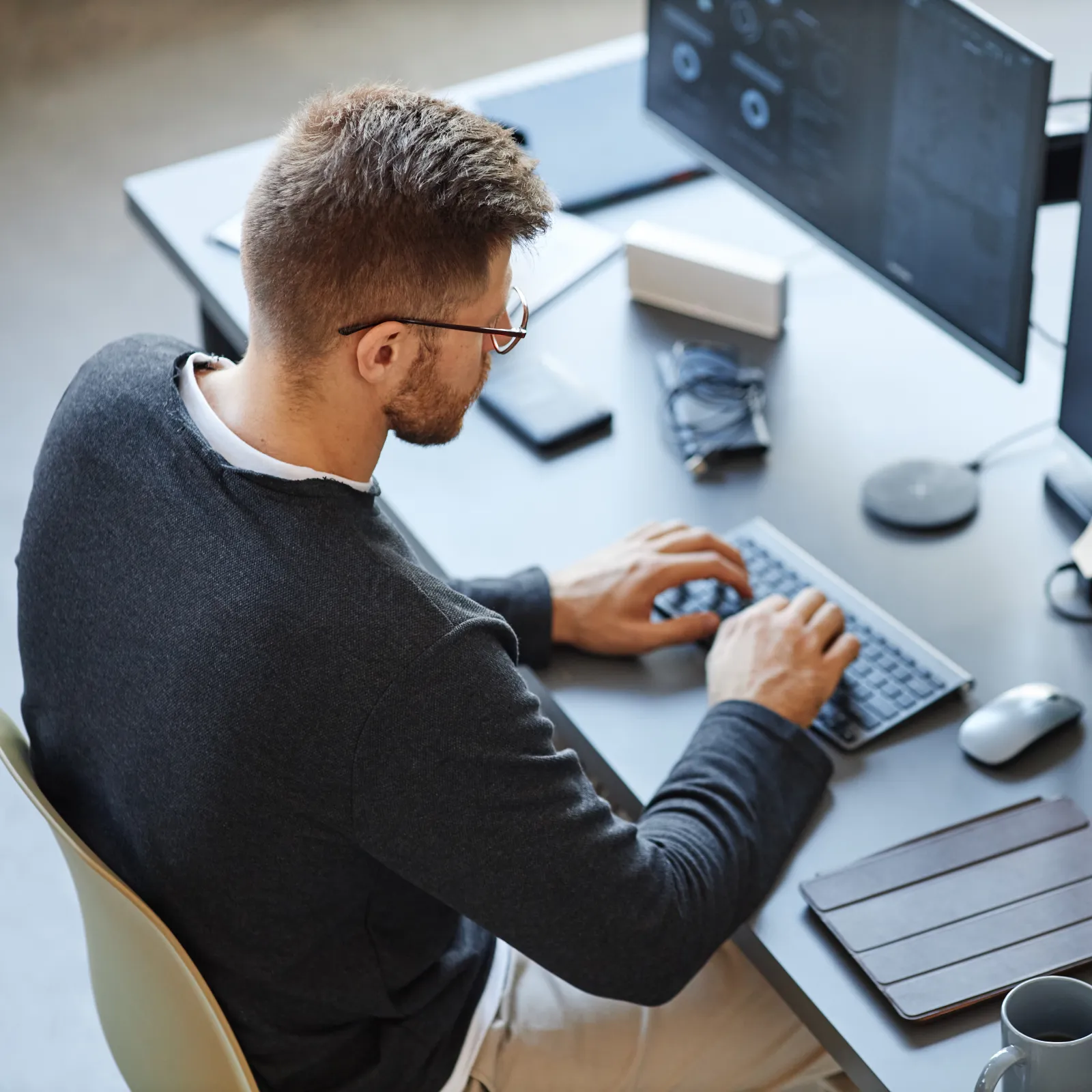 Person working at a desk with multiple monitors displaying code and technology tools.