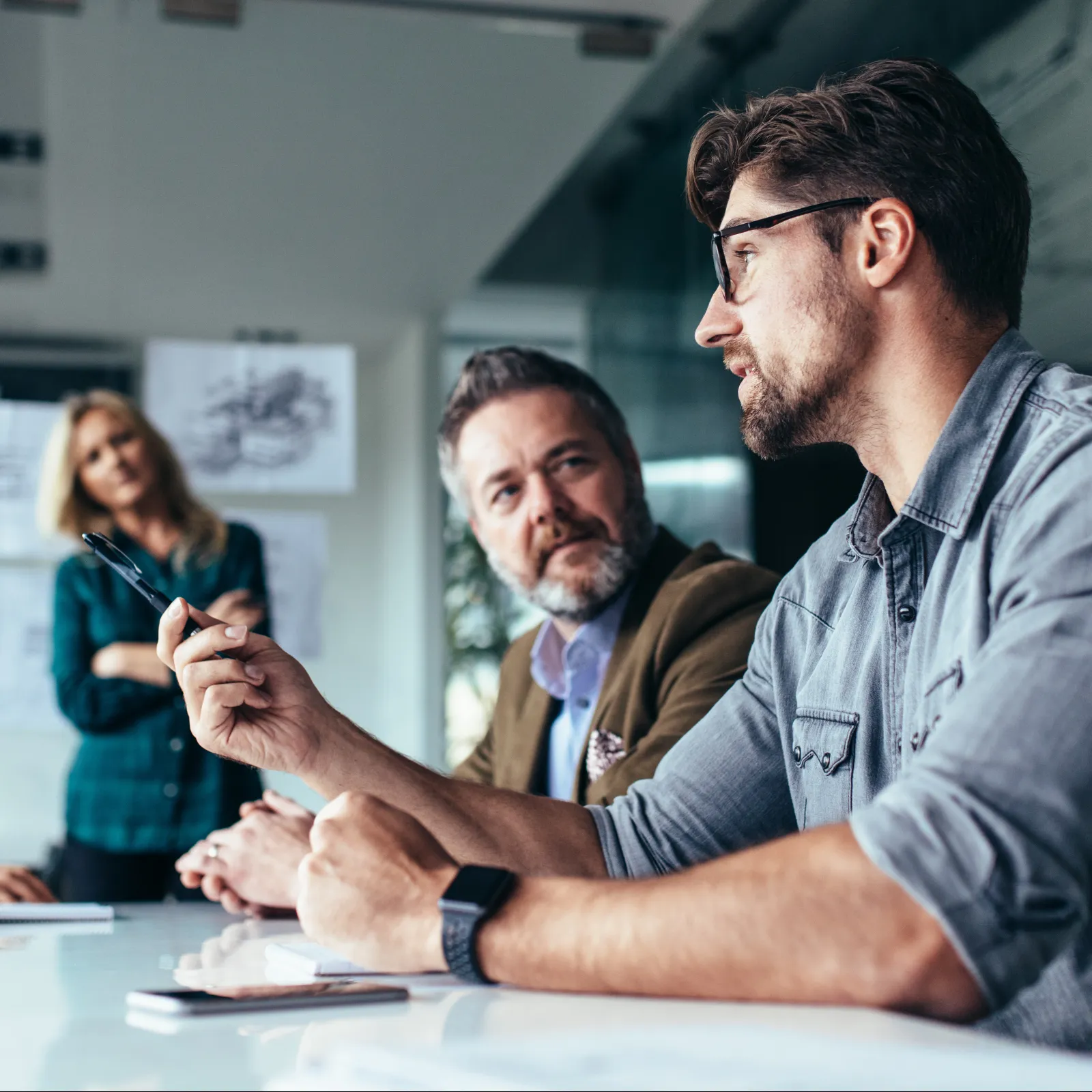 A business meeting with diverse professionals discussing ideas in a modern office setting.