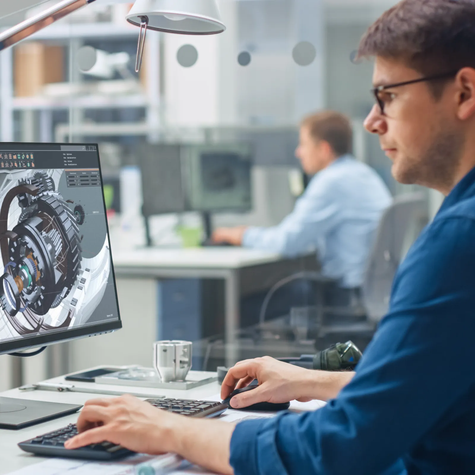 An engineer working on a computer with CAD design in a modern office environment.