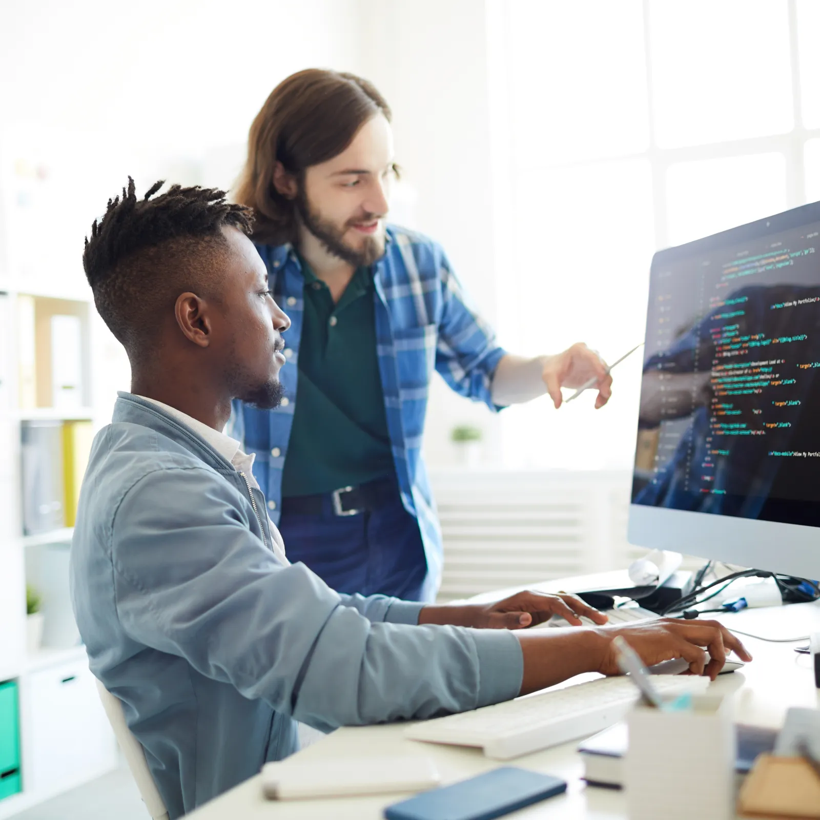 Two software developers collaborating on coding at a modern workspace.