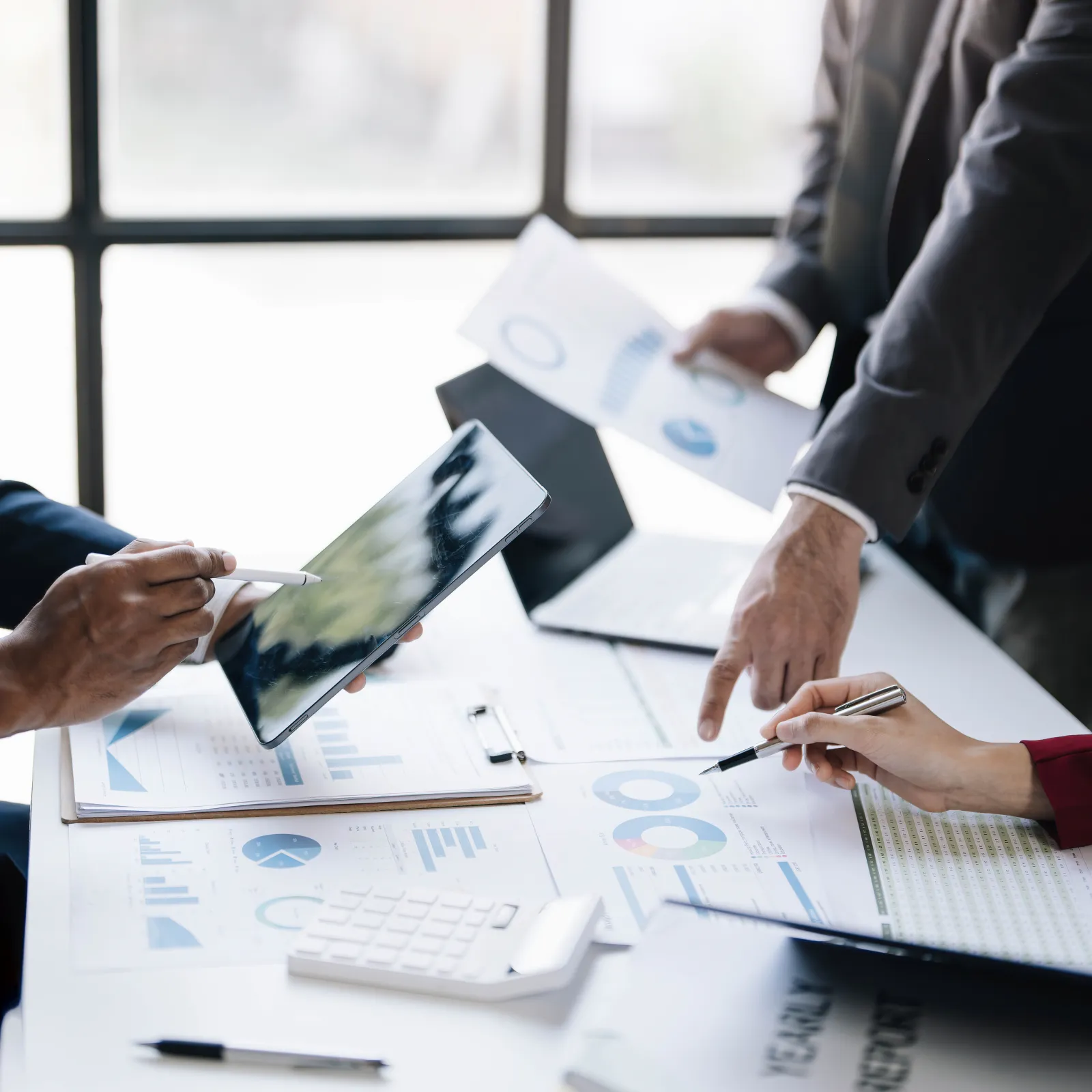 Business professionals analyzing financial reports and data charts in a modern office setting.
