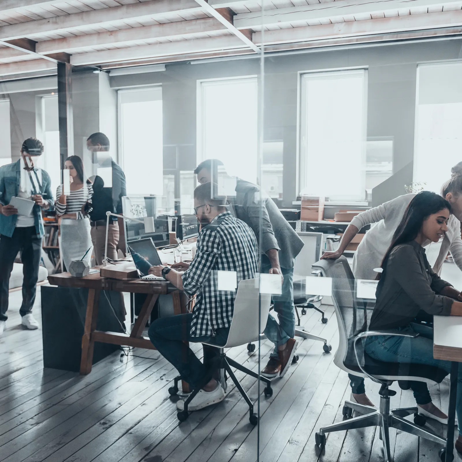 Modern office space with diverse team collaborating on projects and utilizing technology.