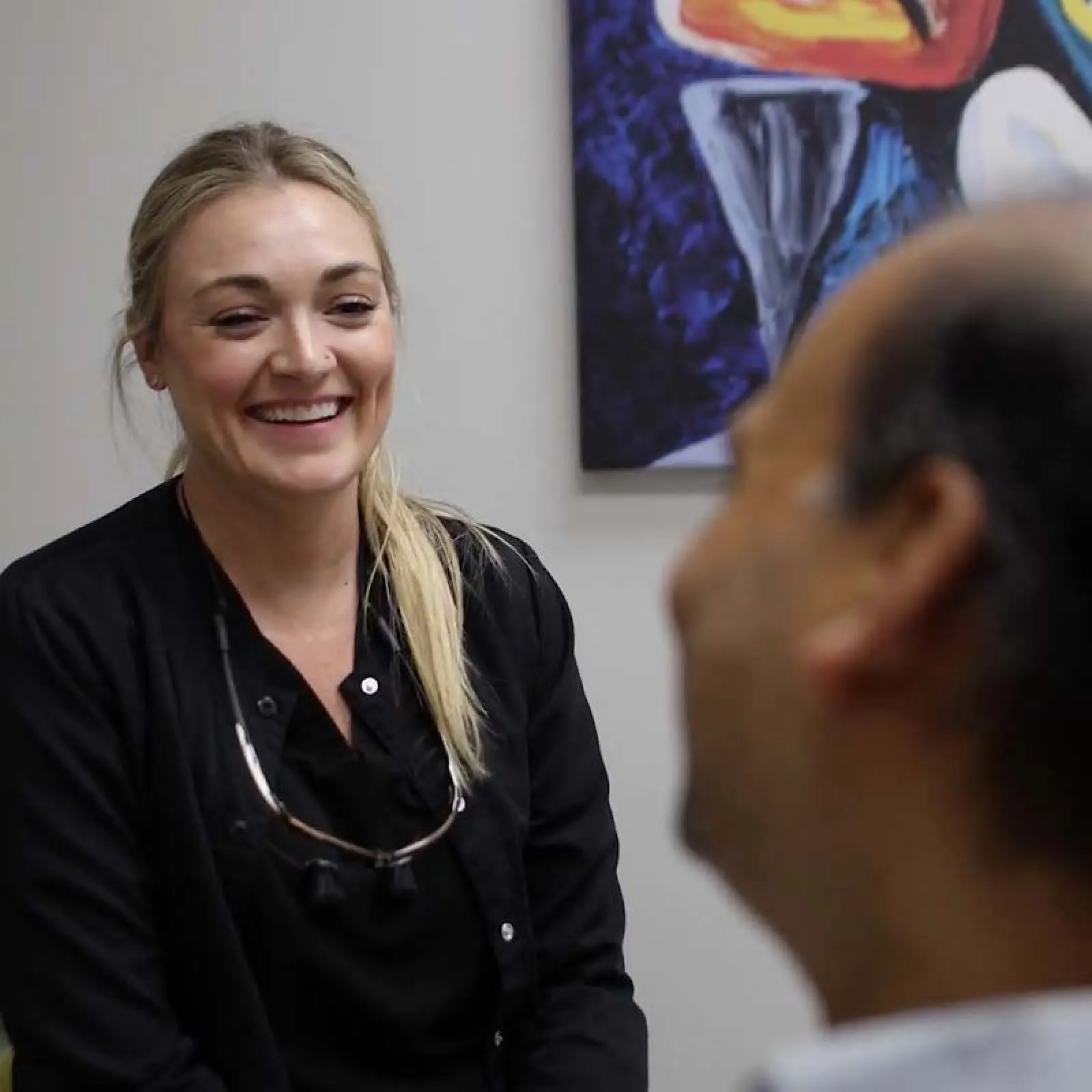 Smiling female dentist talking to a male patient during dental consultation in a clinic.