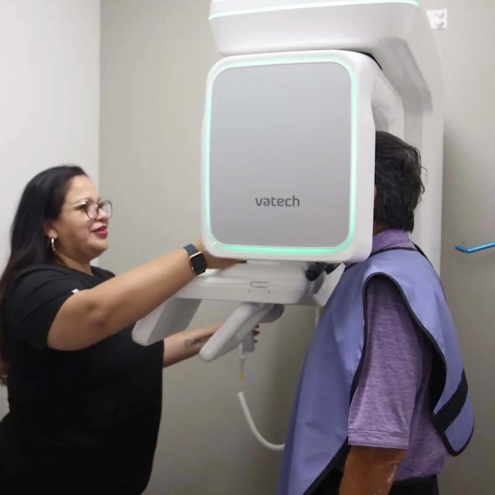 Dental technician assisting patient with a Vatech 3D dental X-ray machine for imaging.