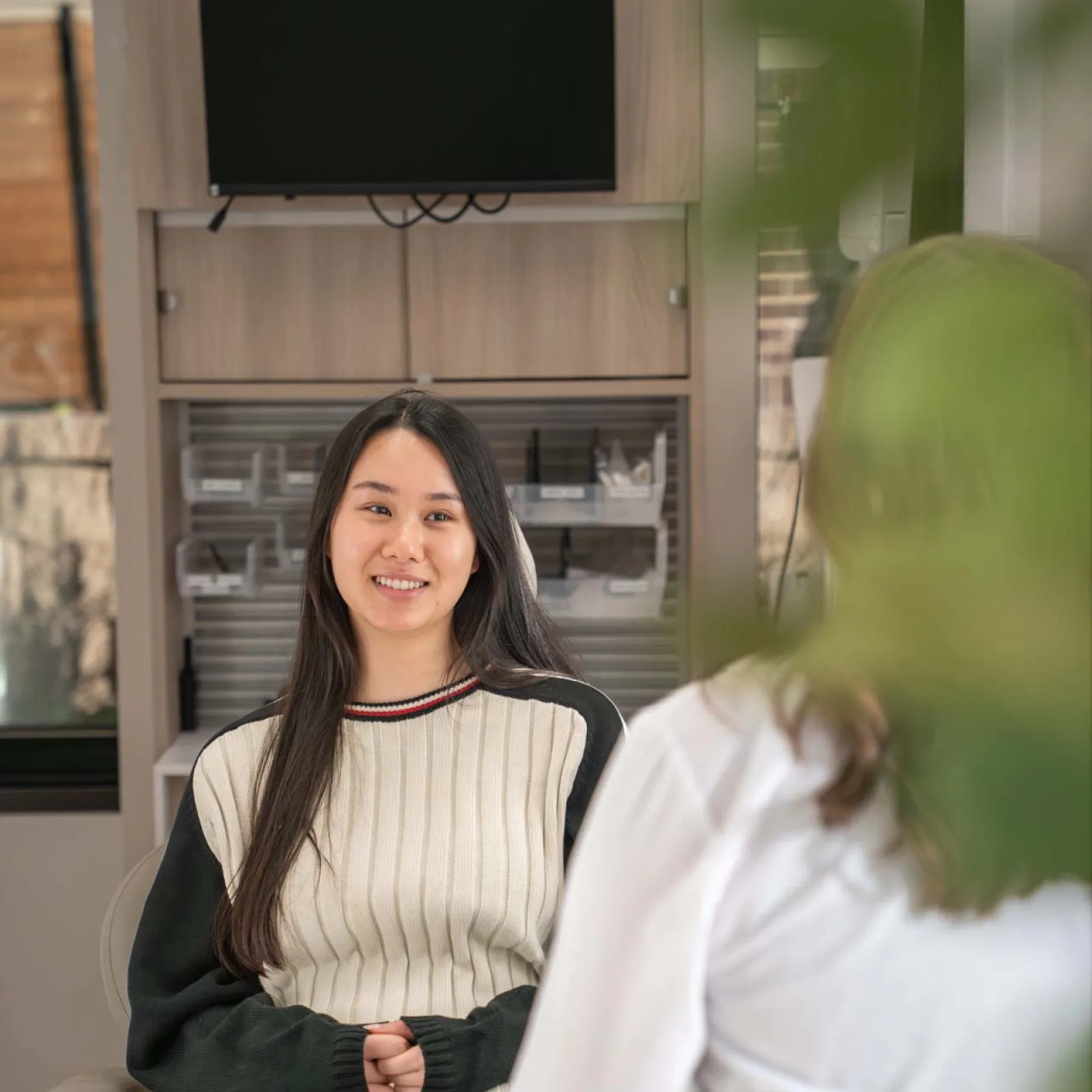 Smiling blonde woman with long hair wearing a white turtleneck and dark blazer with jeweled brooch outdoors.