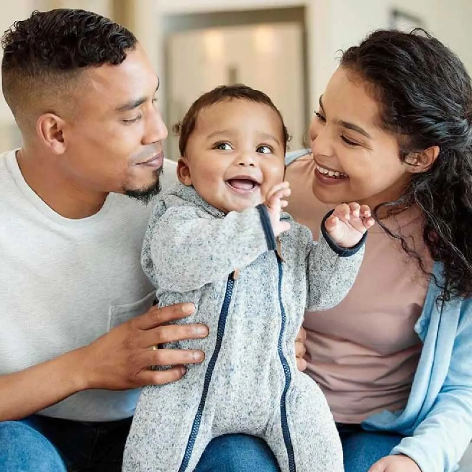 a family smiling and holding a baby