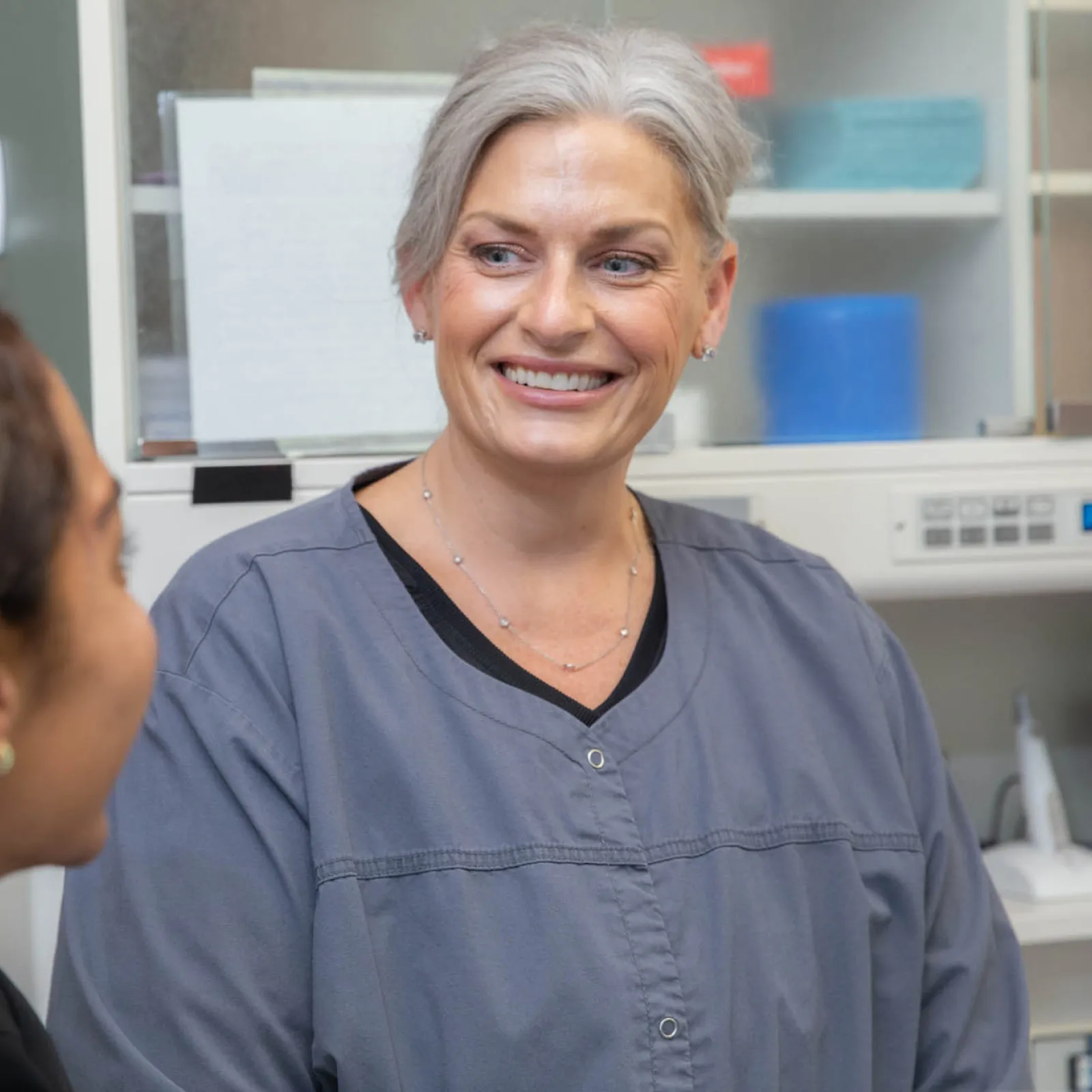 Smiling female healthcare professional talking with a patient in a medical office setting.