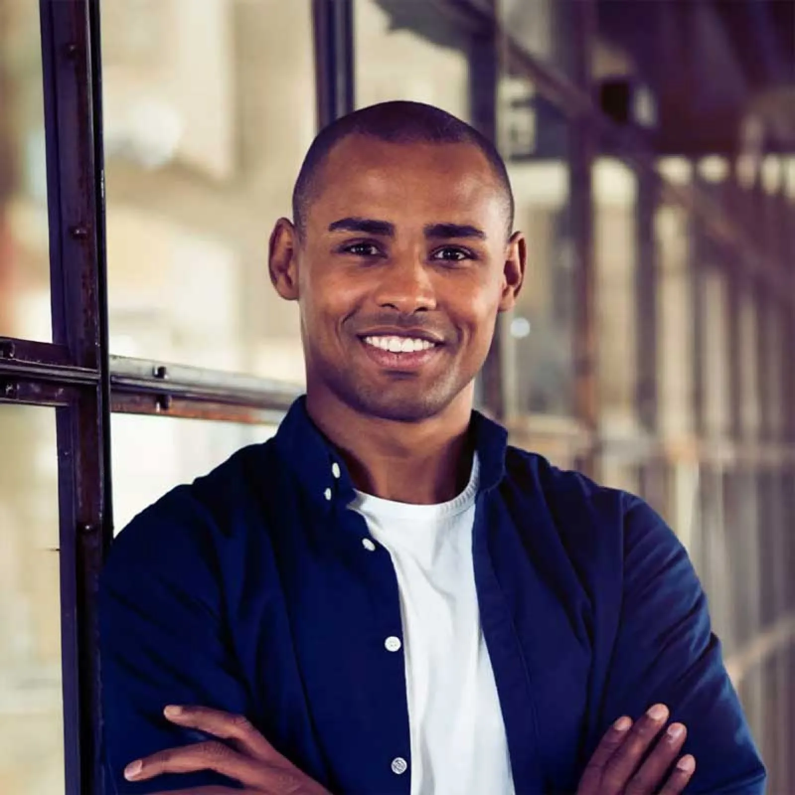 a man smiling with his hands crossed
