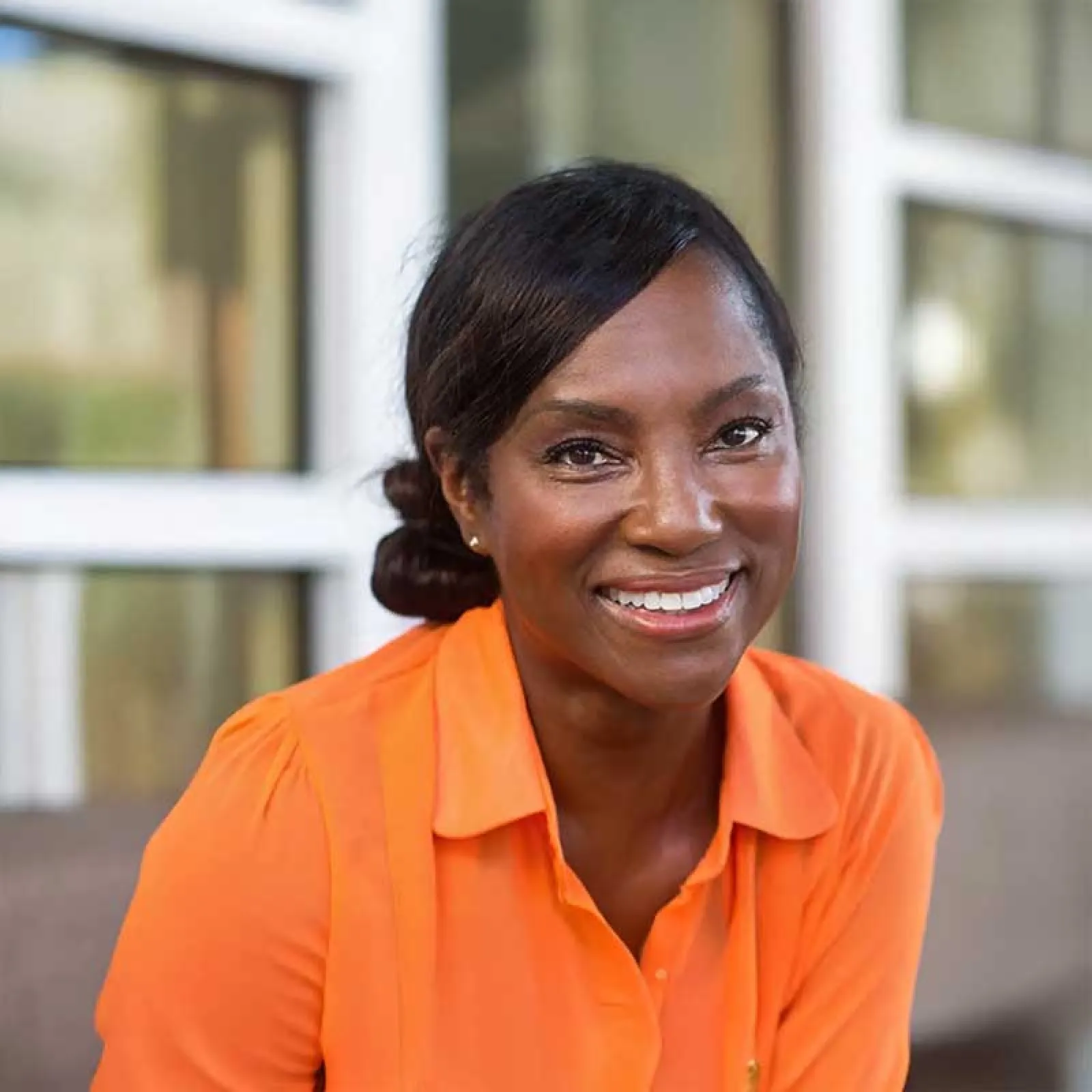 a woman smiling in an orange shirt