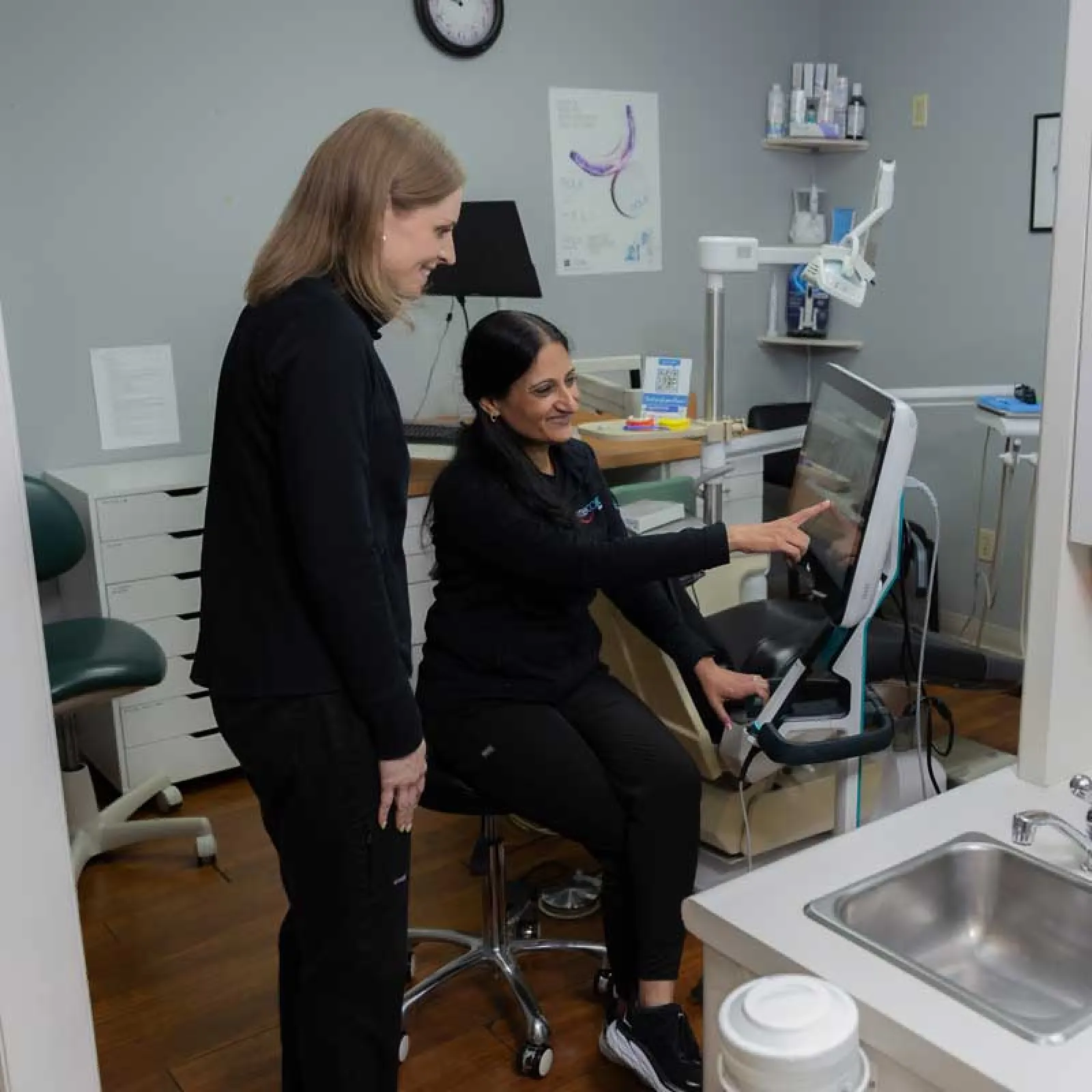 Dentist explaining digital dental X-ray results to patient in modern dental office setting