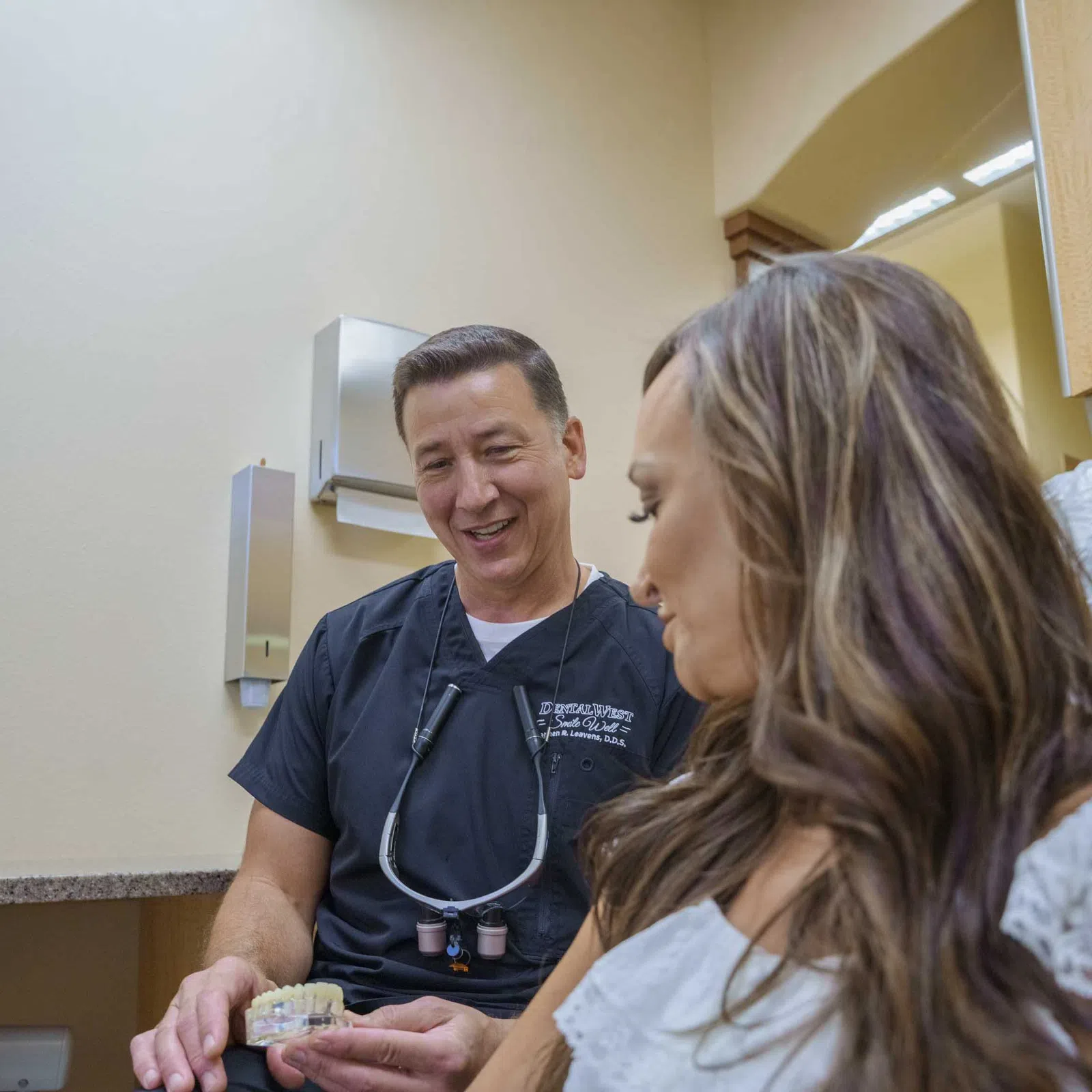 Dentist explaining dental model to female patient in clinic consultation room