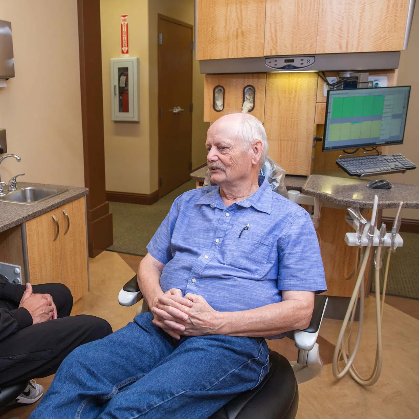 Dentist and senior male patient having a consultation in a modern dental clinic room with equipment.