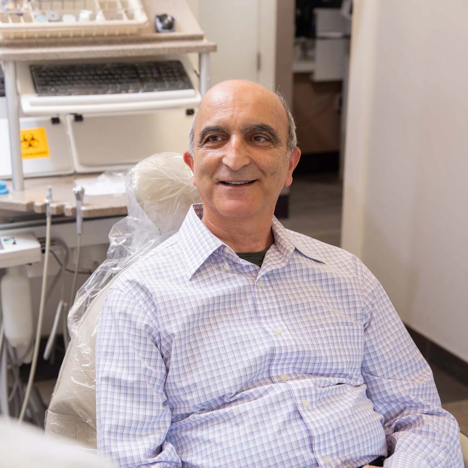 Middle-aged man smiling while sitting in dental chair during consultation with dentist