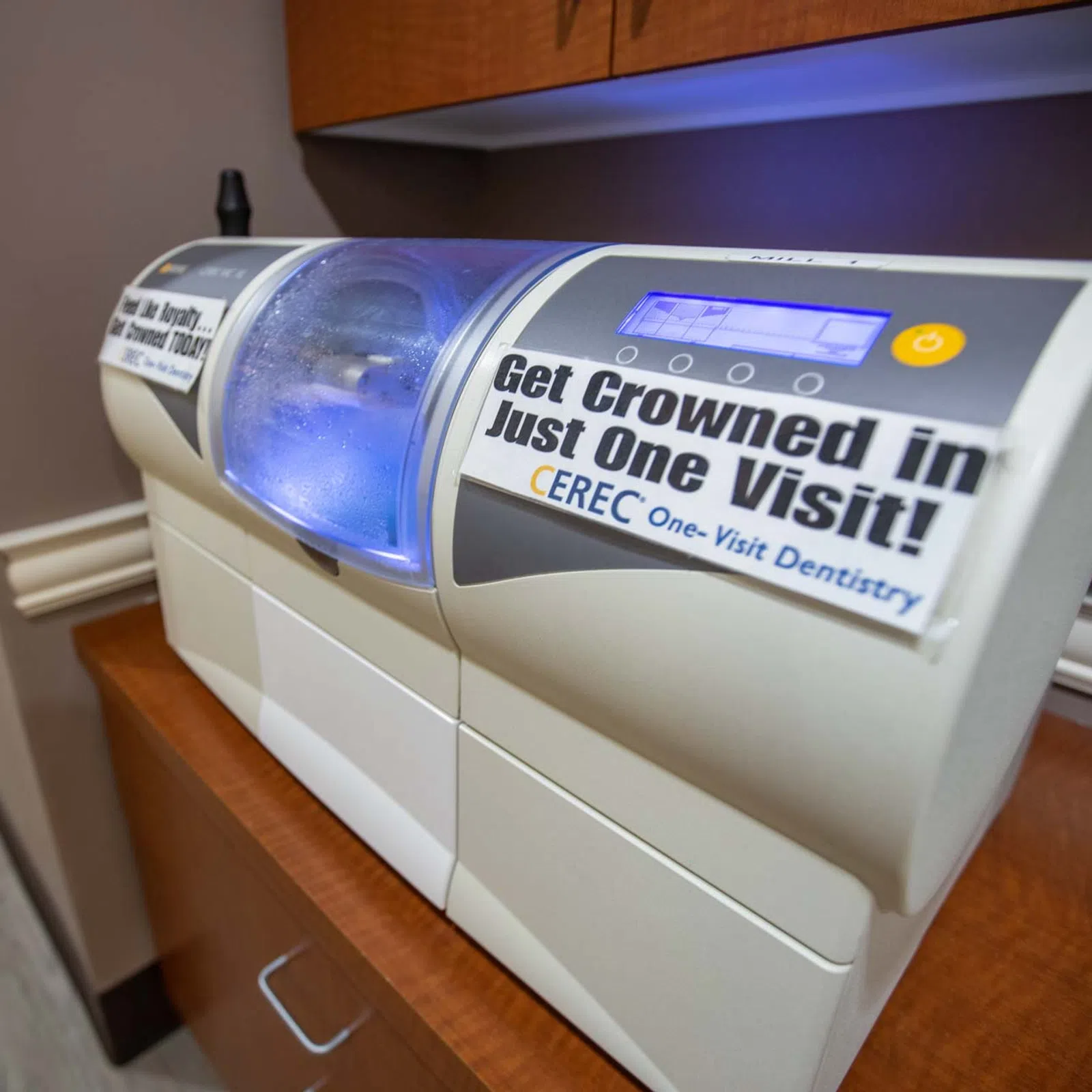 CEREC dental machine in office with sign promoting same-day crown services in one visit.