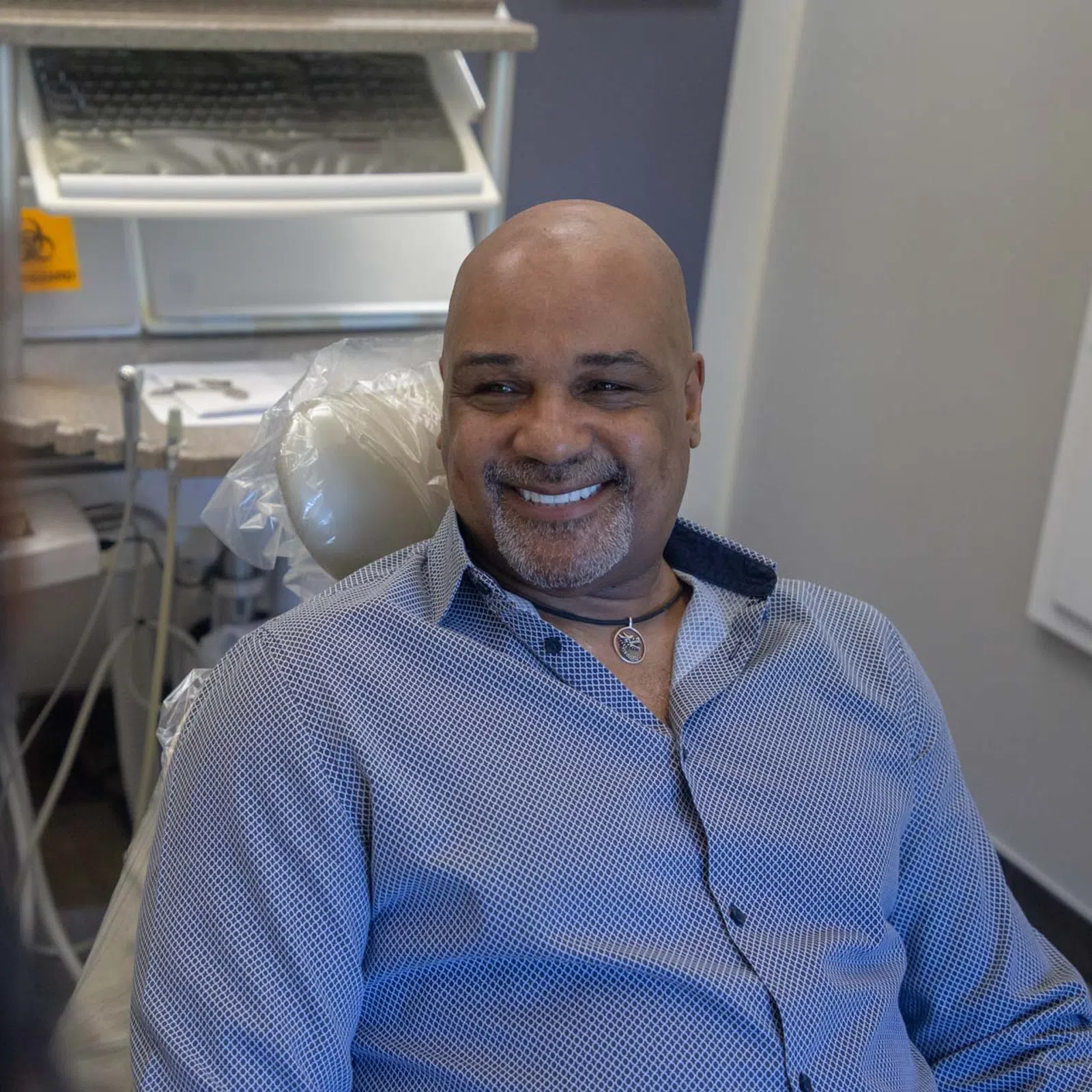 Smiling man sitting in a dental chair during a dental appointment in a modern clinic room.