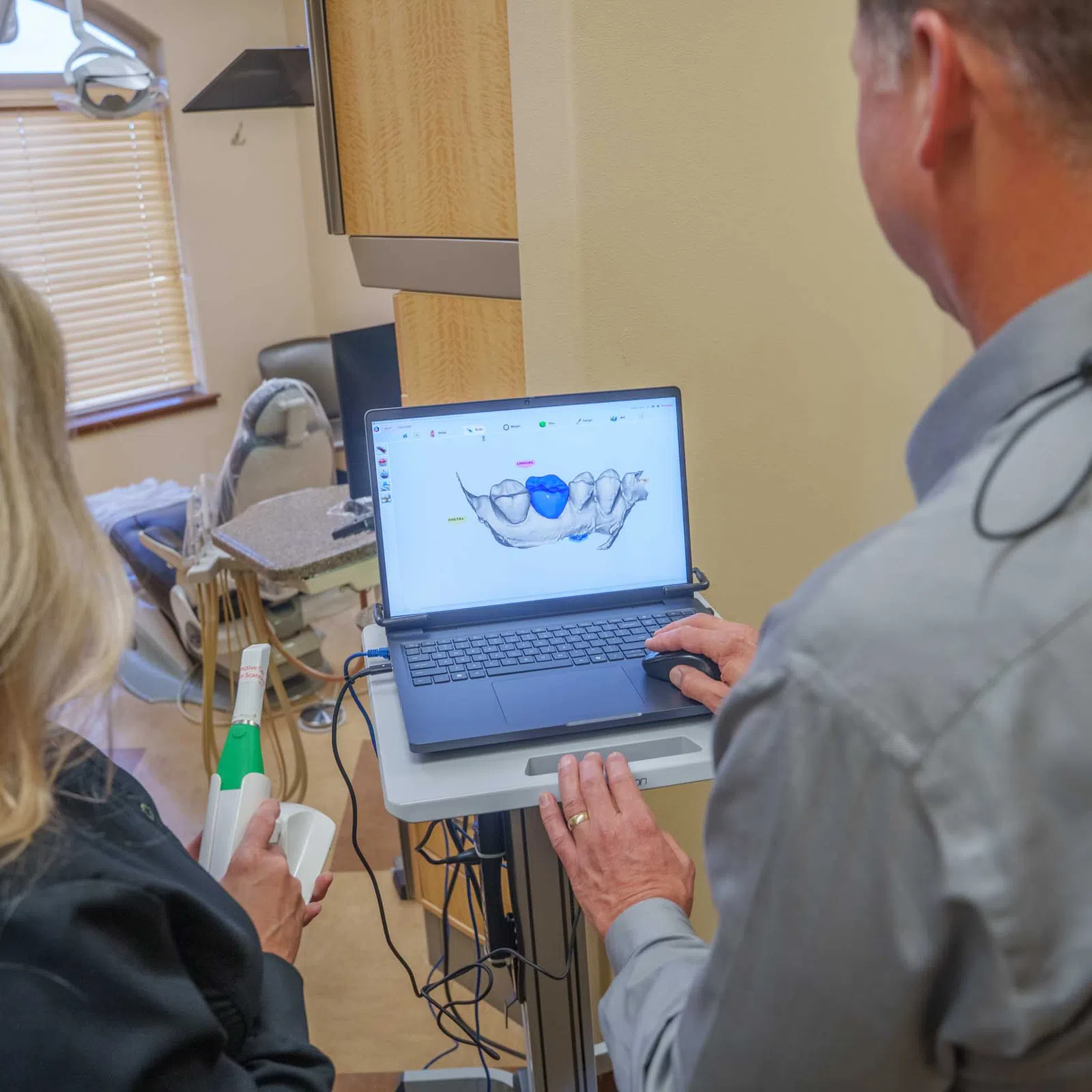 Dental professionals analyzing a 3D digital model of teeth on a laptop in a dental office setting.