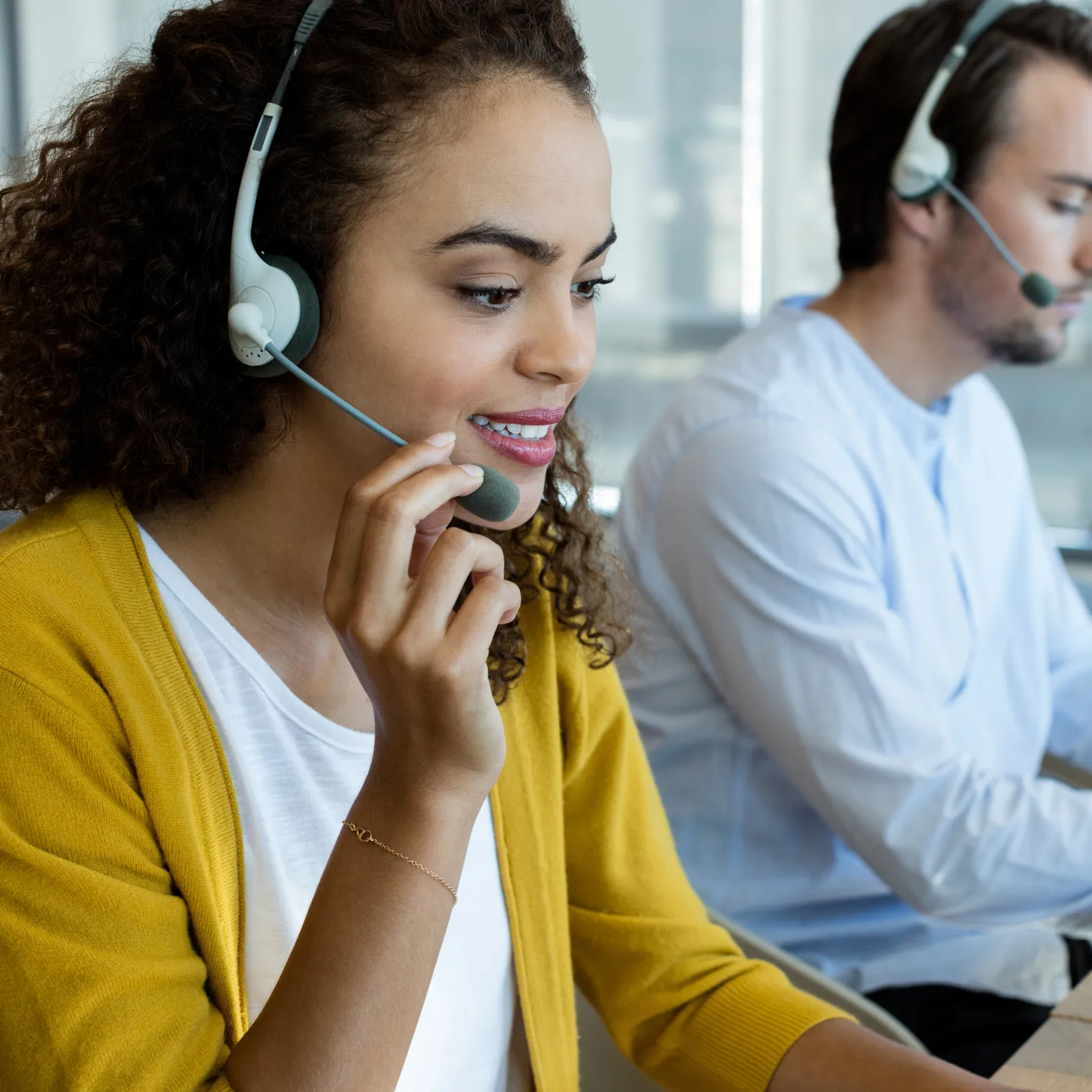 Customer service team wearing headsets working in a modern call center office with focused expressions.