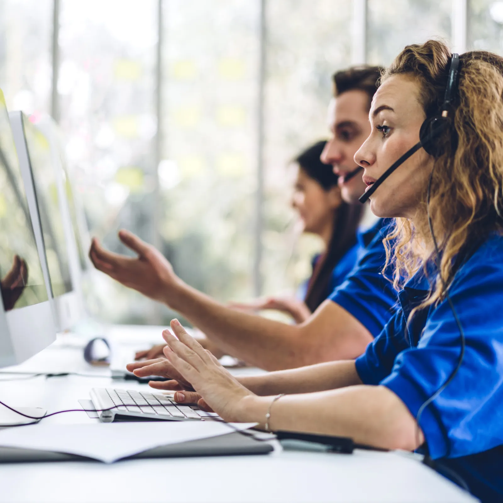 Customer service team wearing headsets working in a modern call center office with focused expressions.