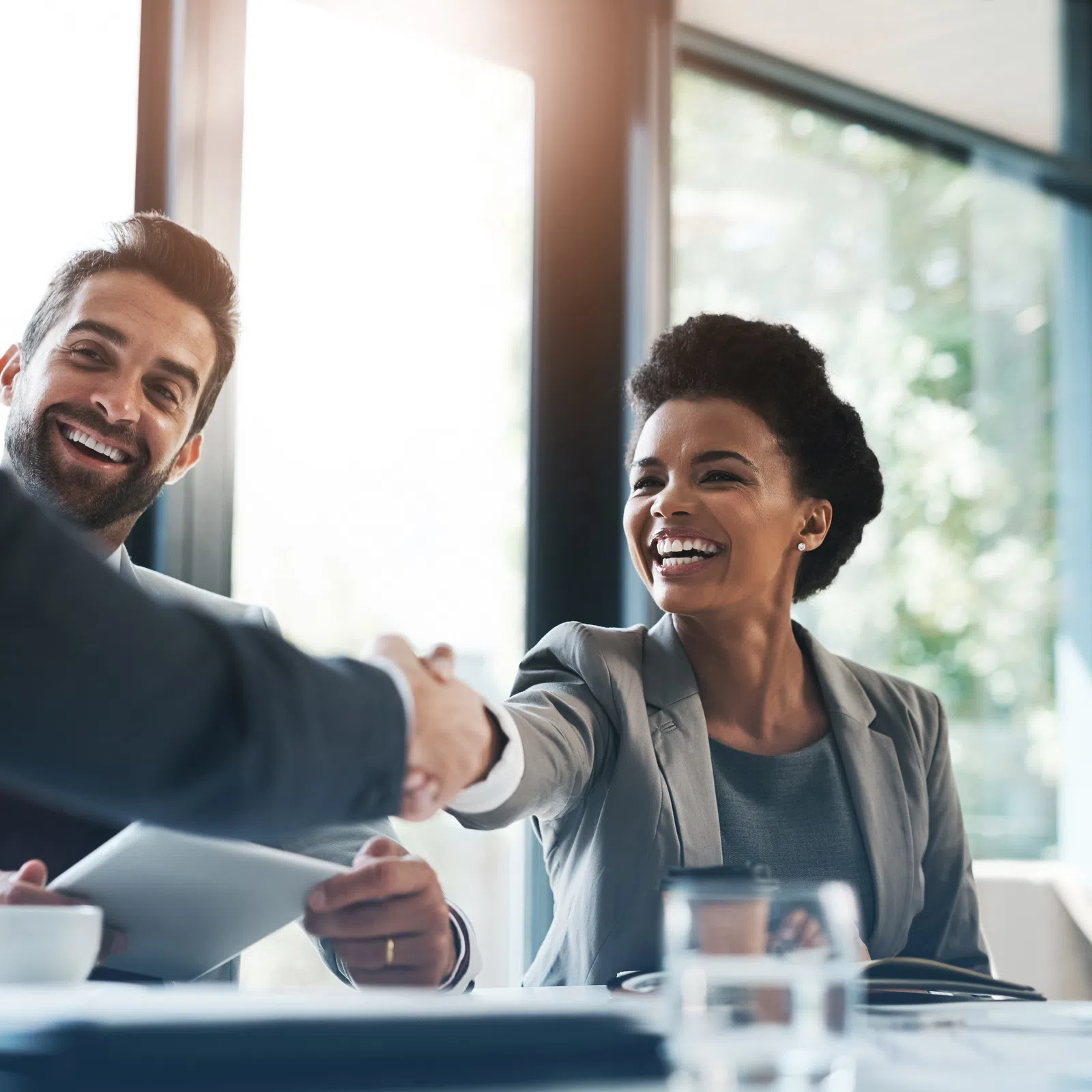 Smiling businesswoman shaking hands with a colleague in a bright modern office during a meeting.