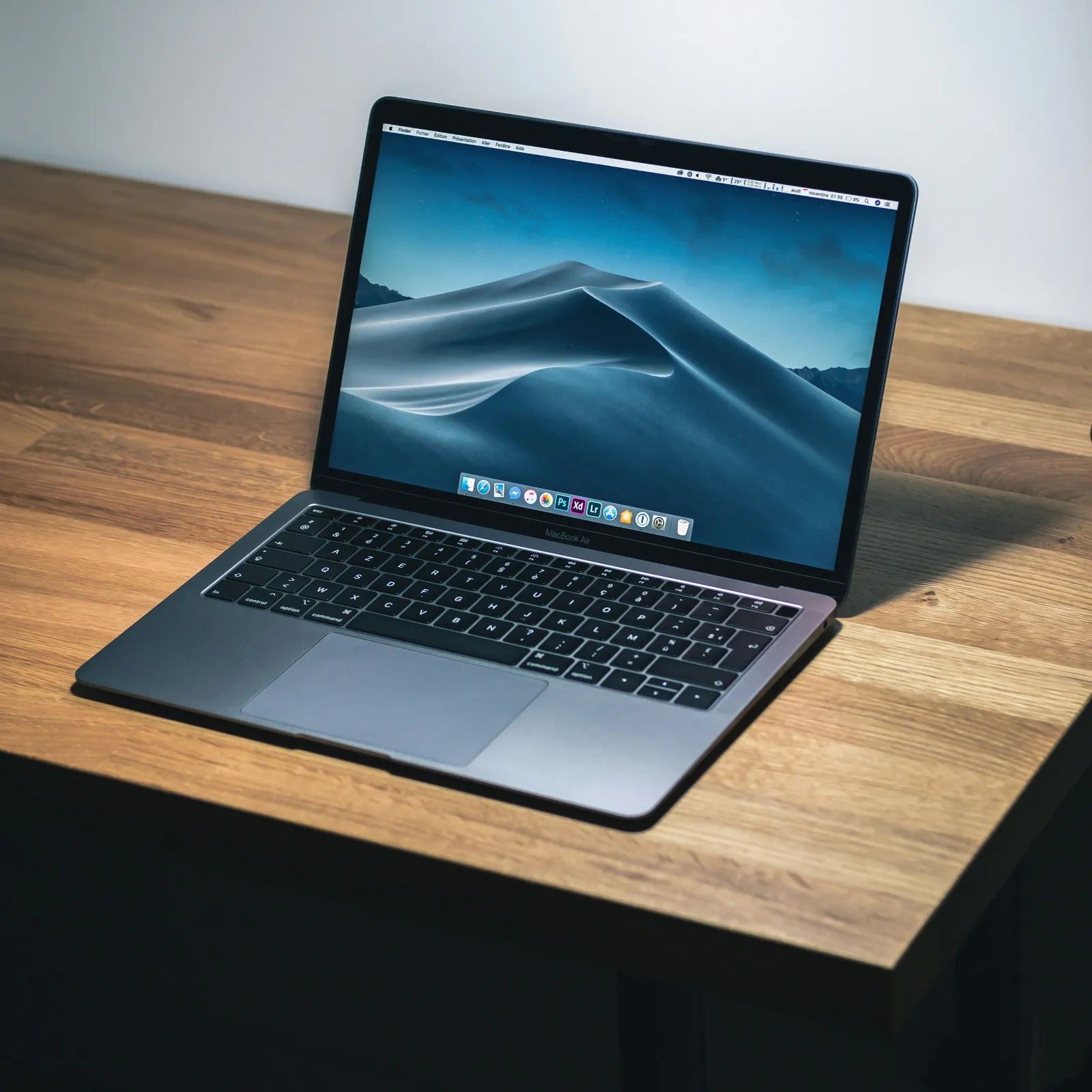 A sleek laptop on a wooden desk, displaying a serene mountain landscape on the screen.