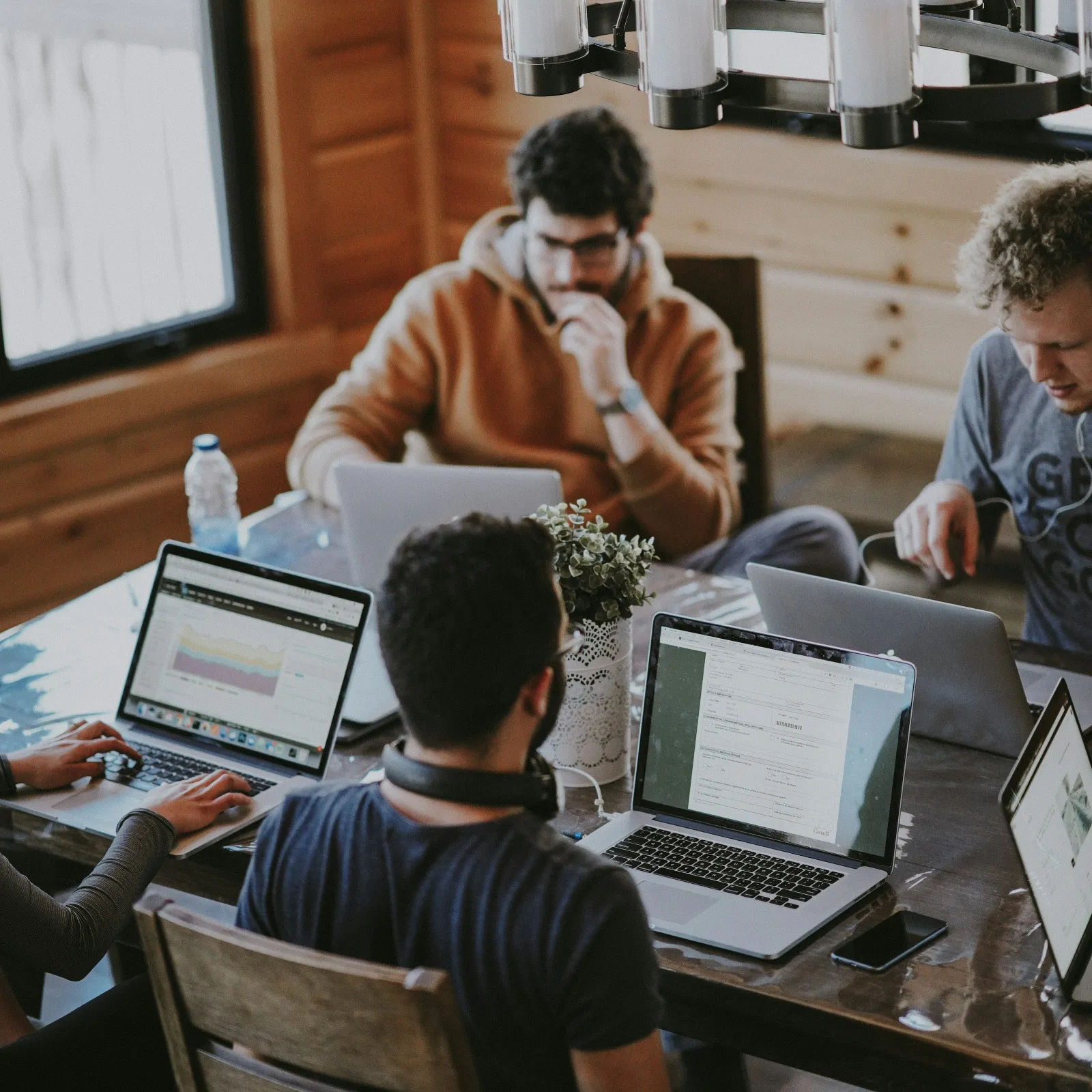 a group of people sitting at a table with laptops