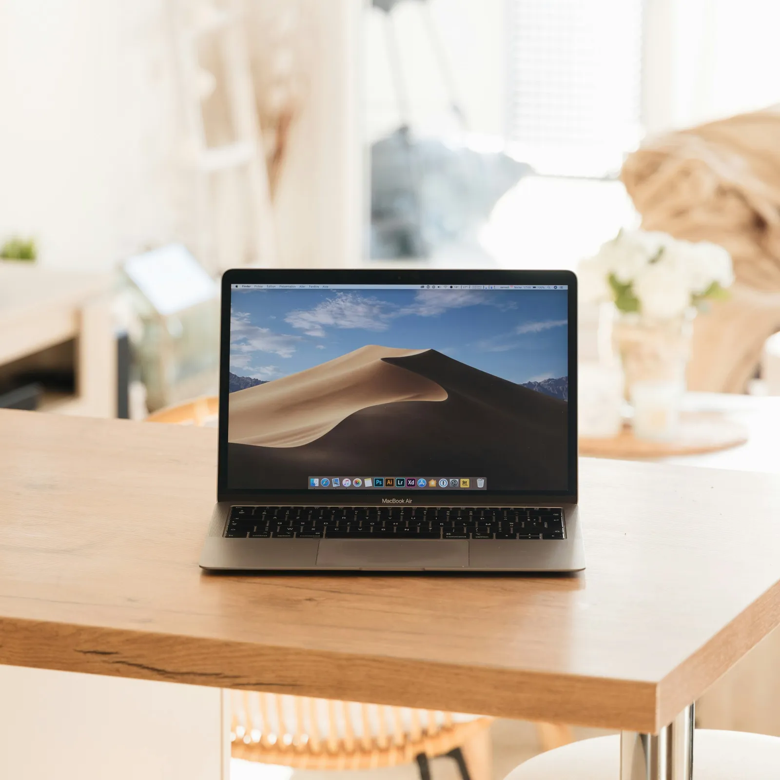 Modern laptop on a wooden table in a bright, stylish home workspace setting.