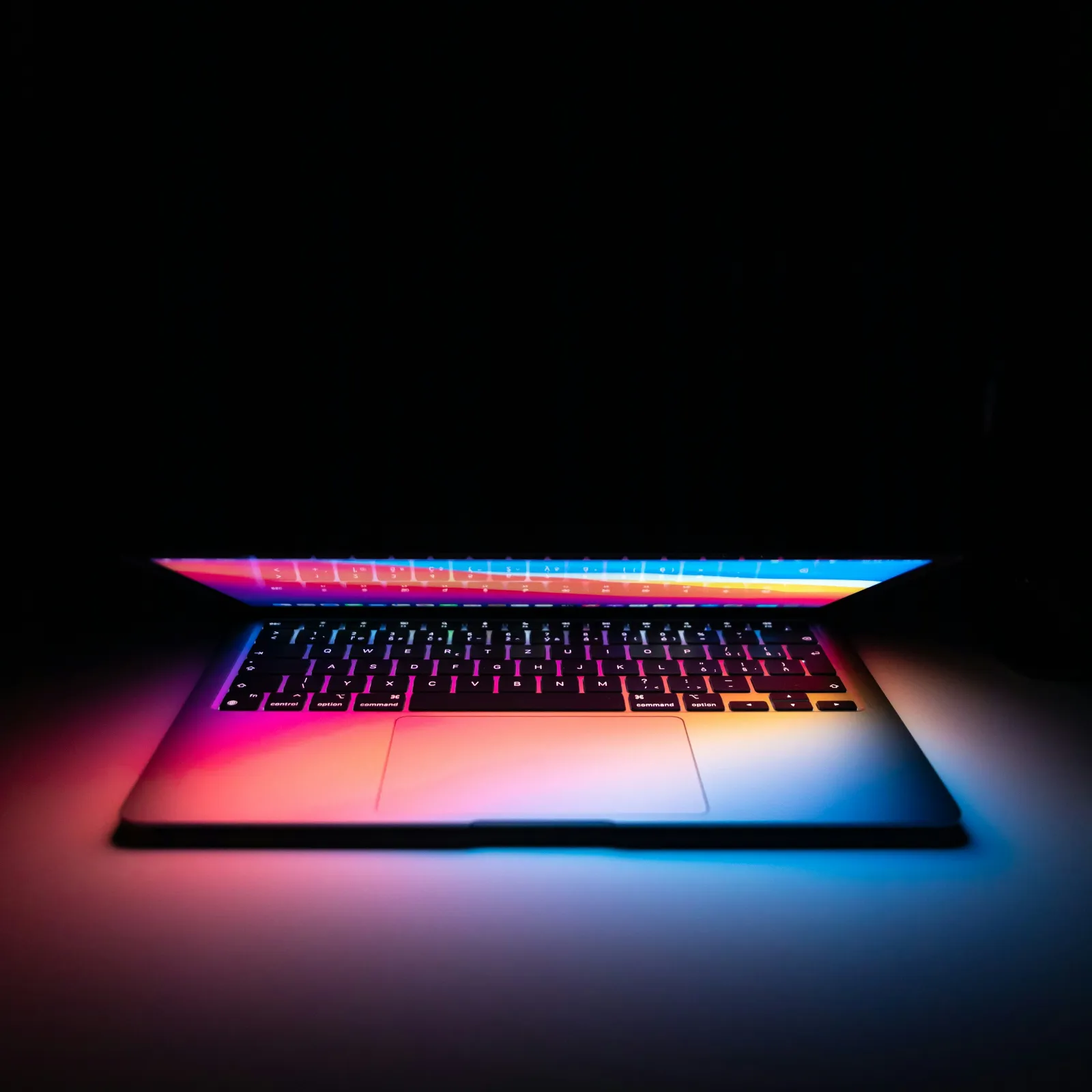 A sleek laptop illuminated with vibrant colors against a dark background.