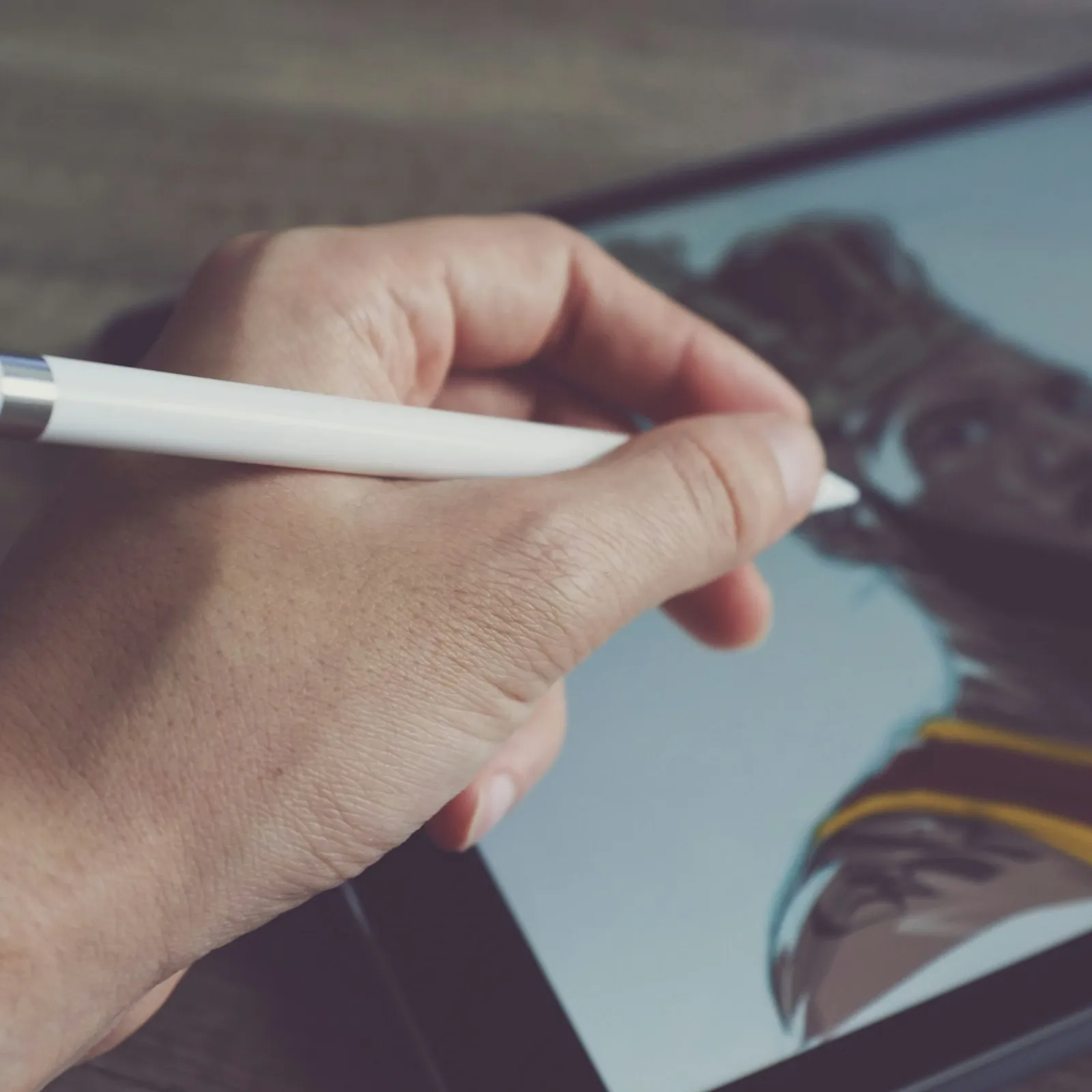 Digital artist illustrating a portrait on a tablet with a stylus in hand.