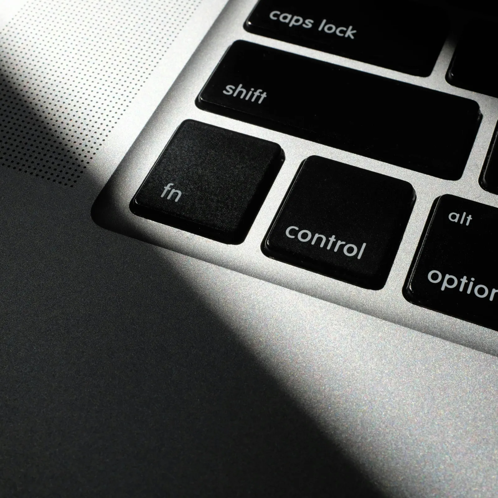 Close-up of a laptop keyboard showing keys in shadow and light contrast.