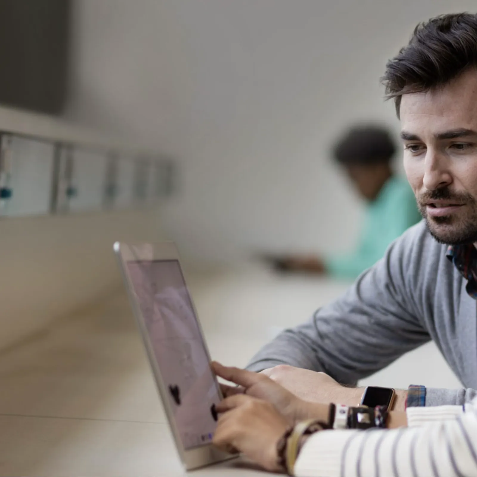 Two colleagues collaborating and reviewing information on a laptop in a modern workspace with natural light.