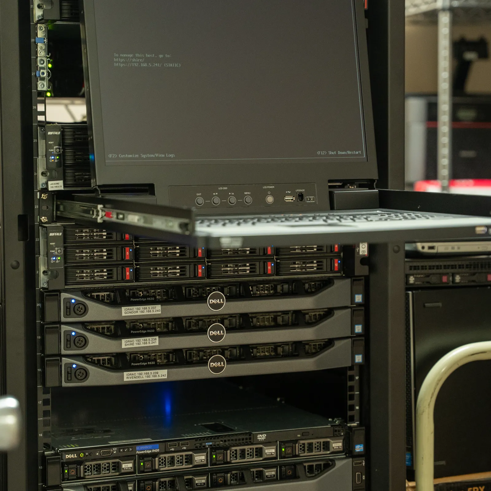 Rack-mounted Dell servers with a pull-out monitor displaying system information in a data center environment.
