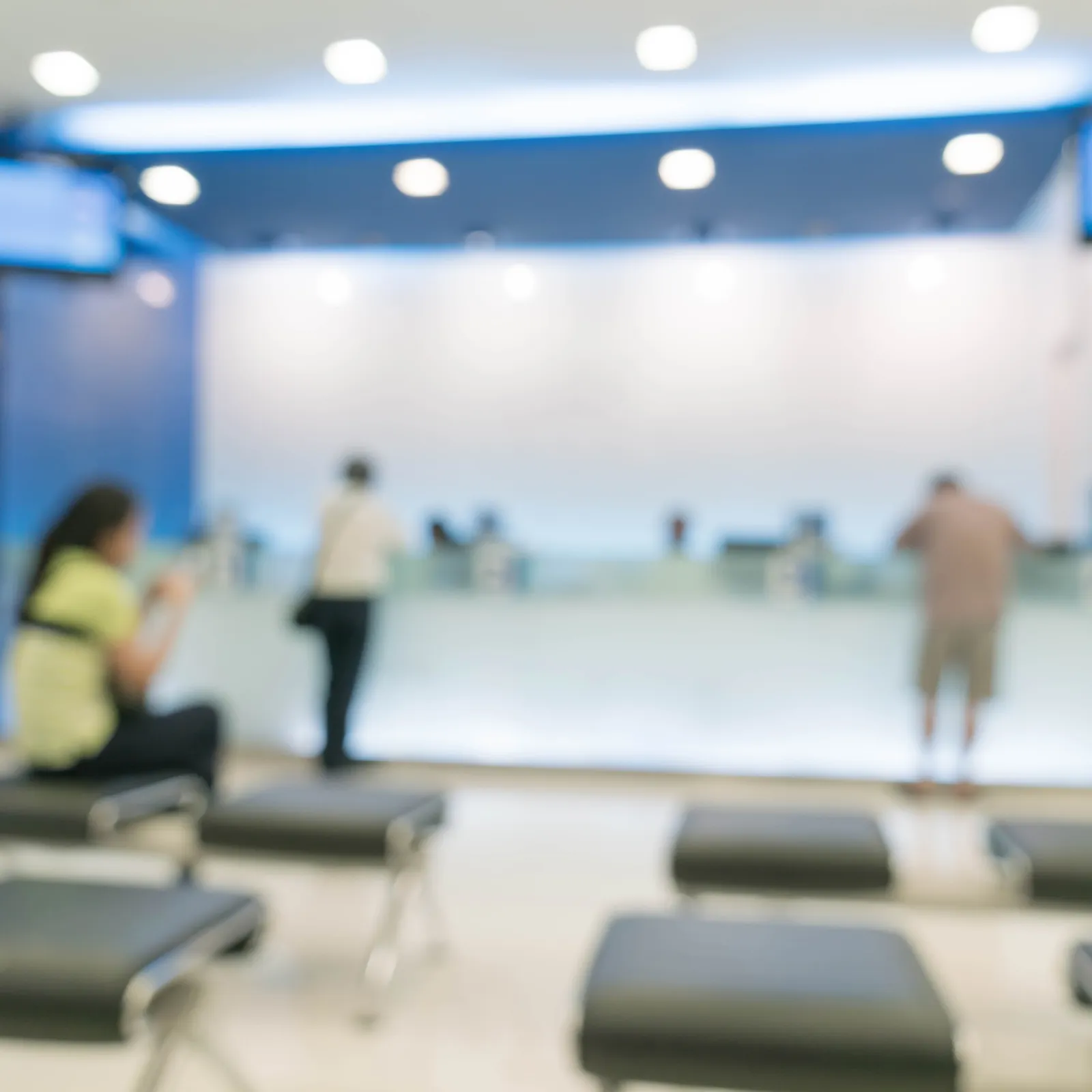 Blurred interior of a waiting area with benches and people at a service counter.