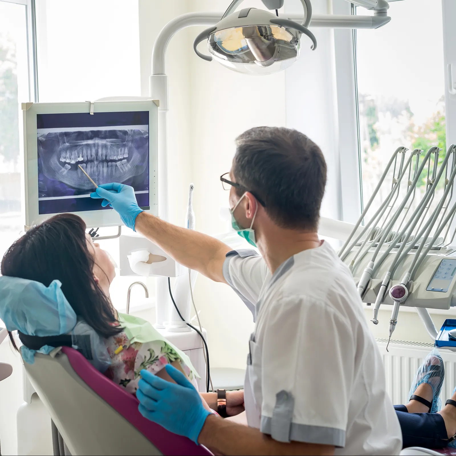 Dentist showing dental x-ray to a patient in a modern clinic setting.
