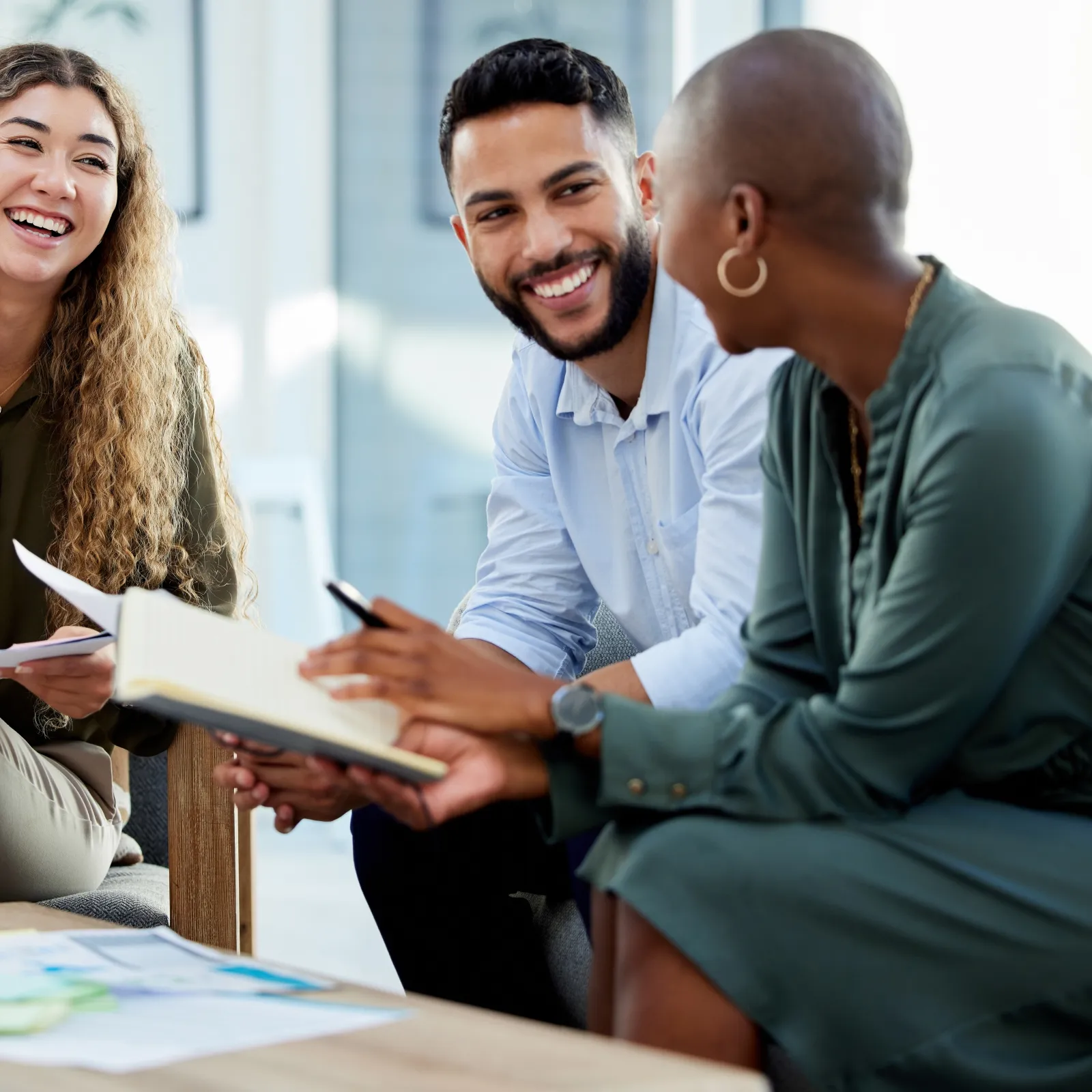 Three diverse professionals discussing ideas in an open, modern office space.